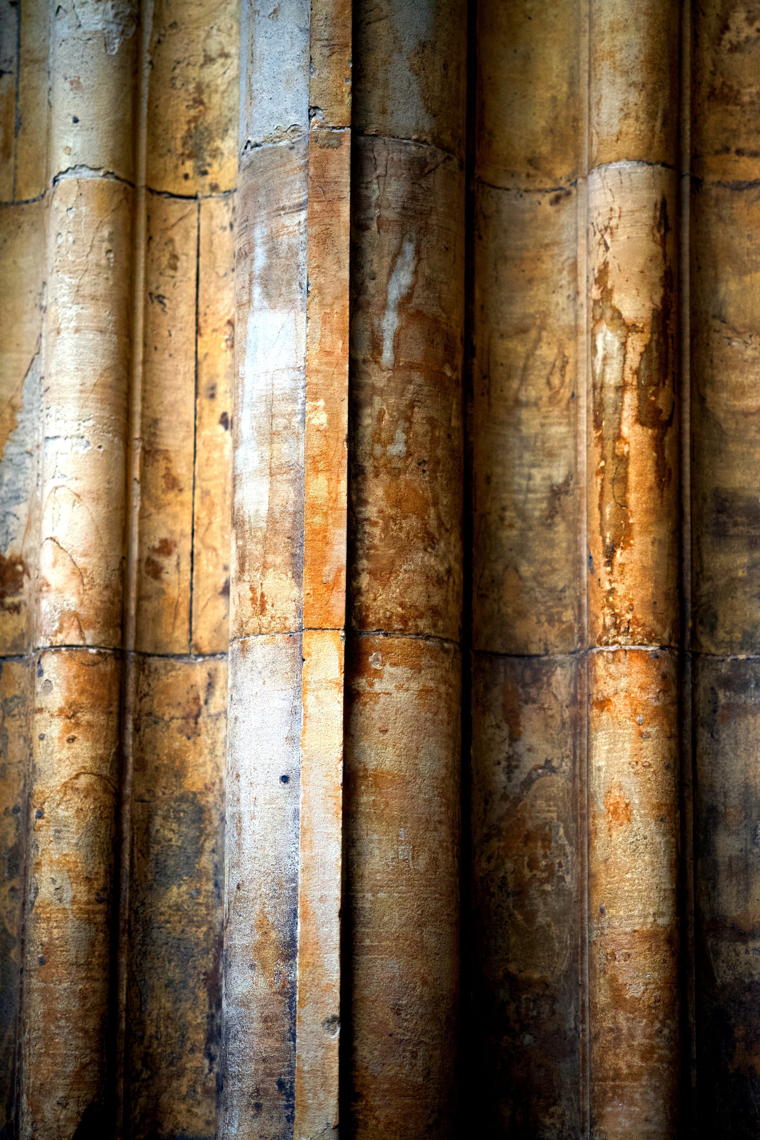 A close-up view of ancient, weathered stone columns with a rough surface and warm, earthy tones.