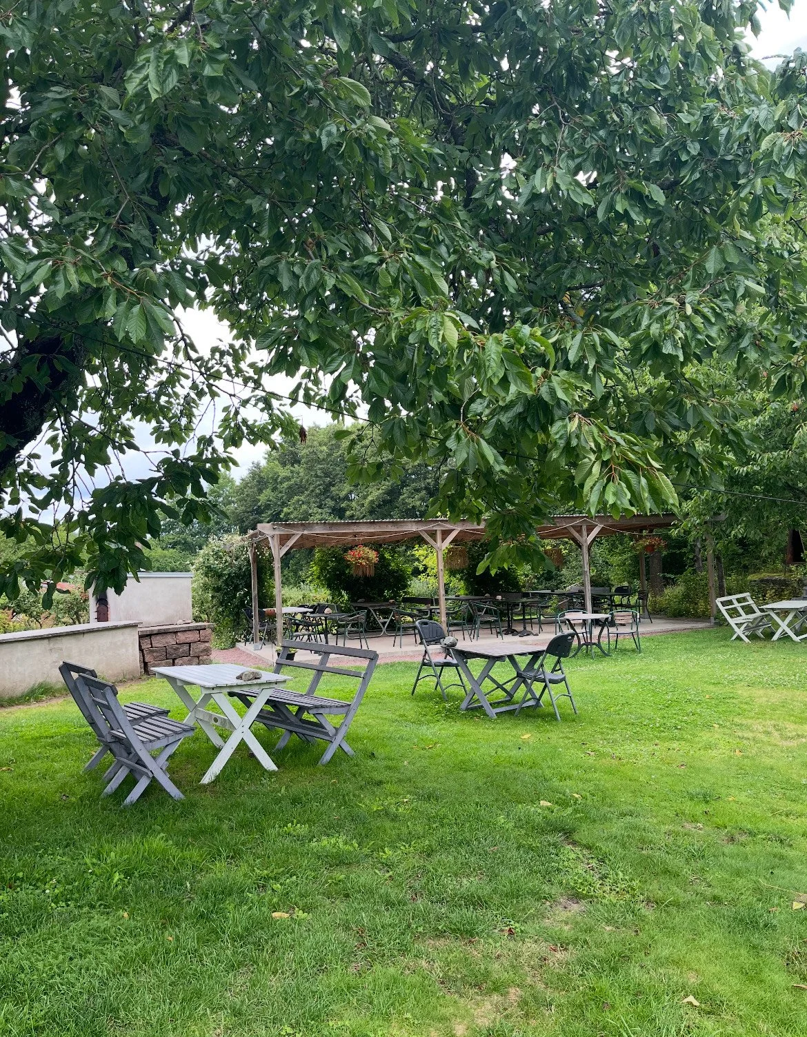 Uteservering med trämöbler under pergola.