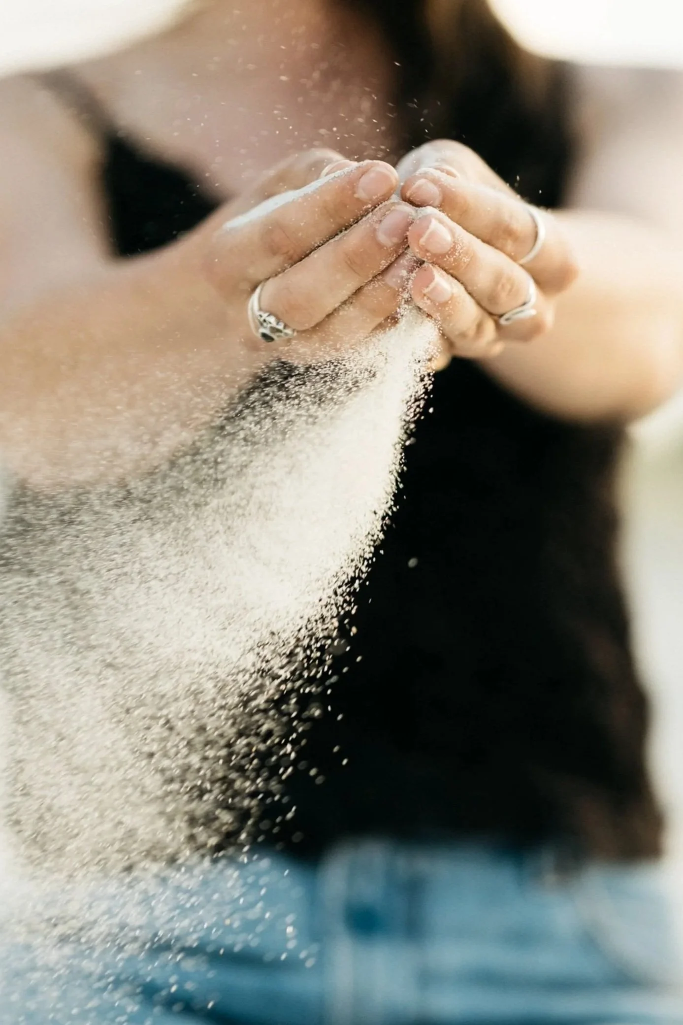 A person sifting flour with their hands, with flour falling through their fingers.