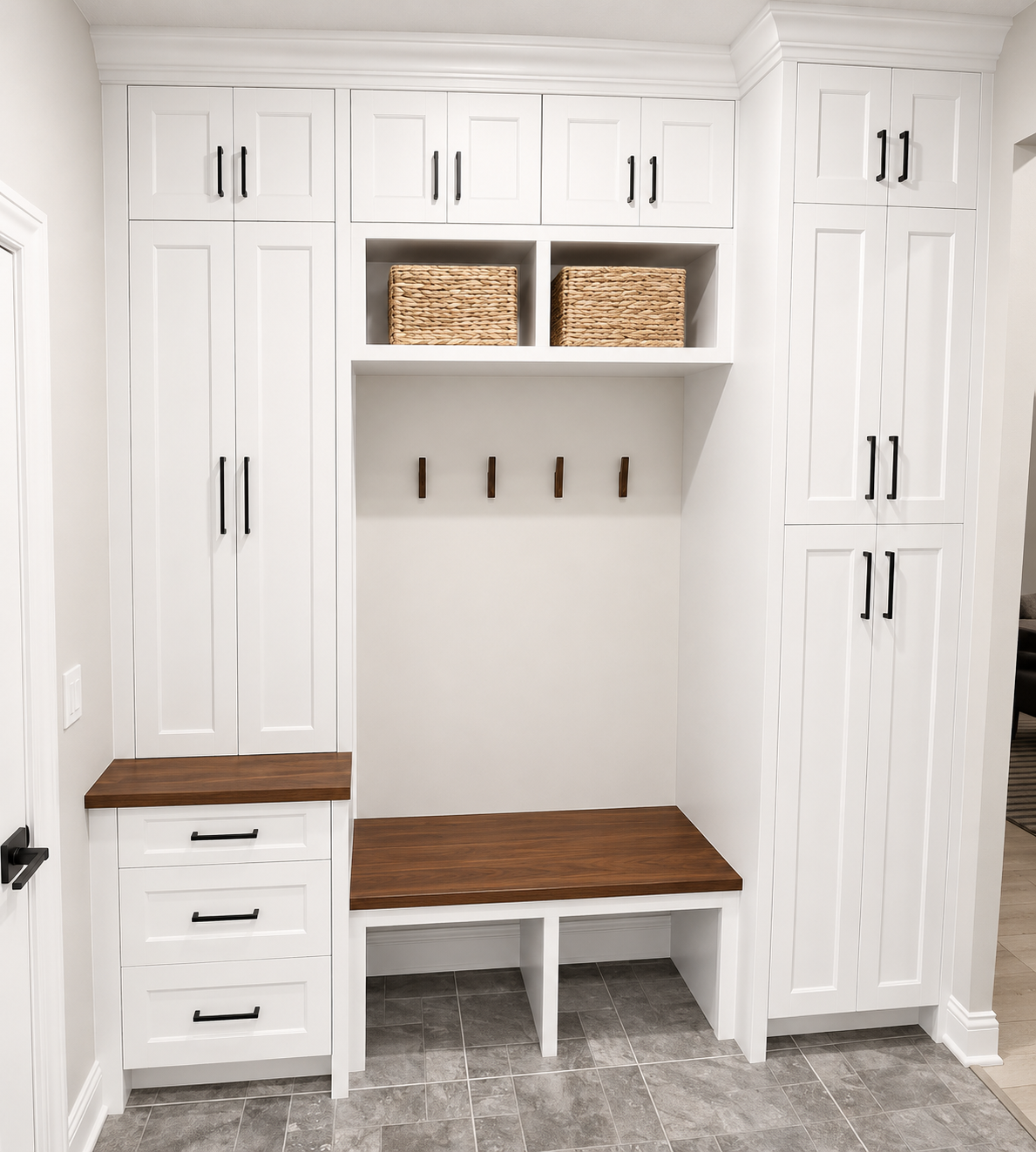 White hallway with built-in storage, black handles, wooden benches, woven baskets, and hooks.