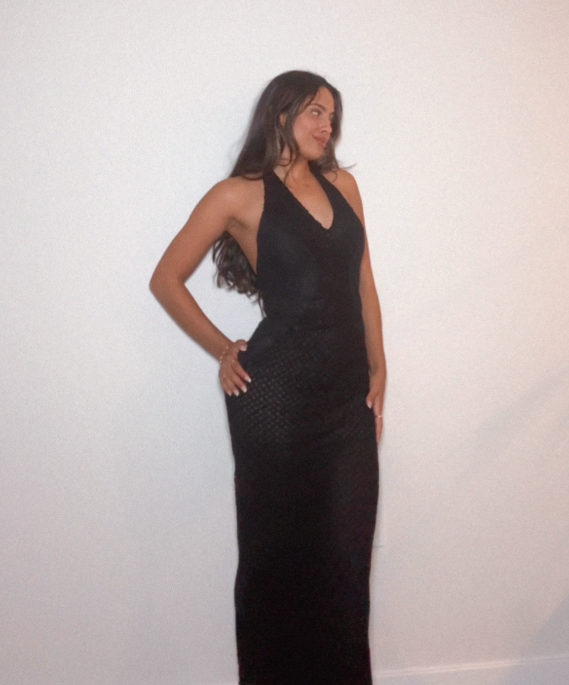 model wearing a gown from Gianni Versace 2002 by Donatella. It features a sheer fishnet sexy gown in black, with a corset like front.