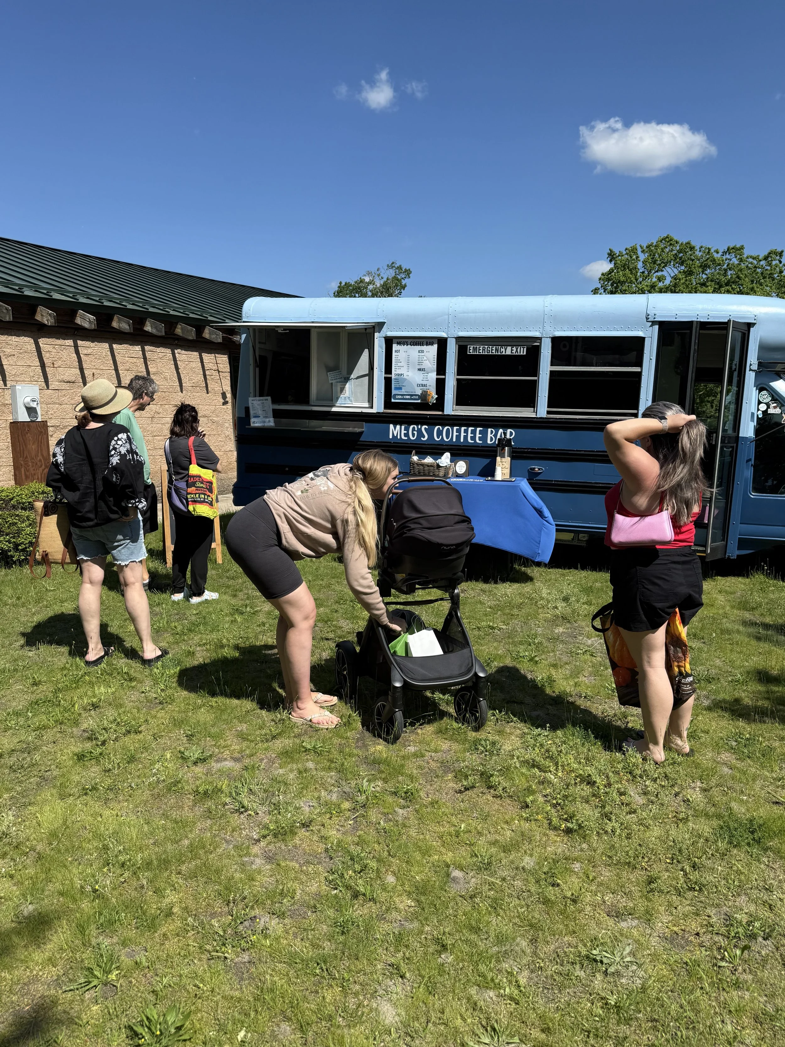 People standing in line in front of a blue food truck, outdoors on a sunny day. Howell Farmers market by Hear Here Events 2026 season