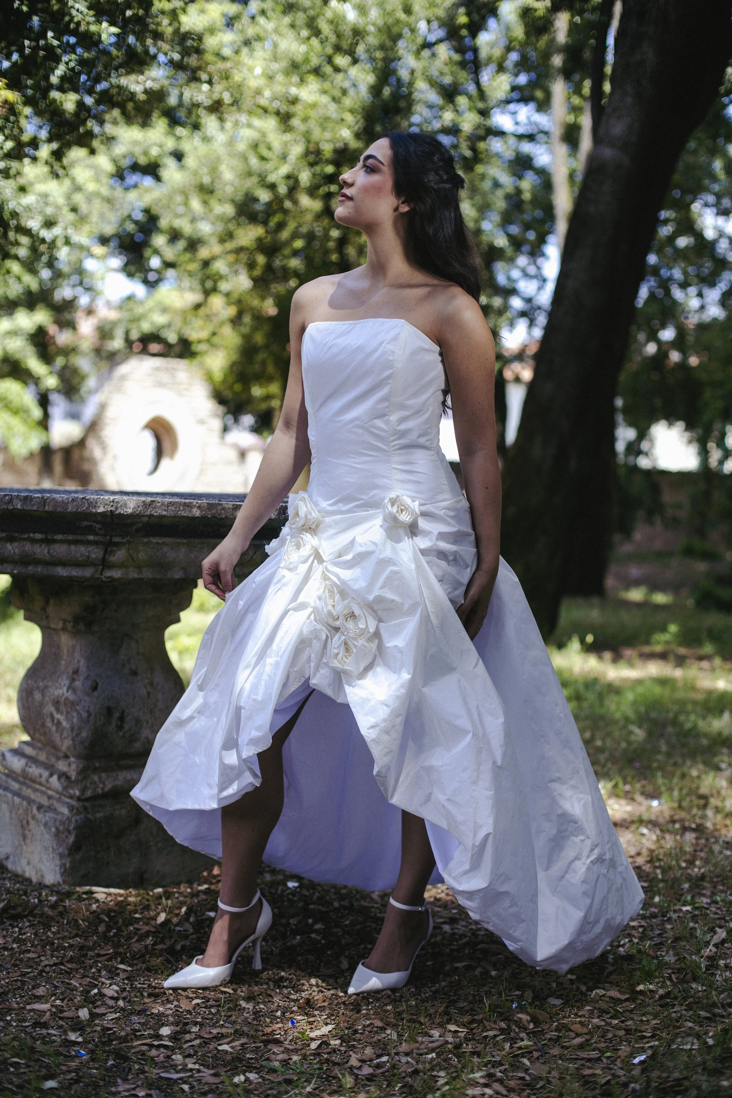 Rosa
Starting from €1,550
A dramatic strapless bridal gown in 100% silk taffeta, featuring an asymmetric draped skirt with a front slit and handcrafted silk roses at the hip. The lace-up back adds a bold, sculptural finish. A gown that balances roman