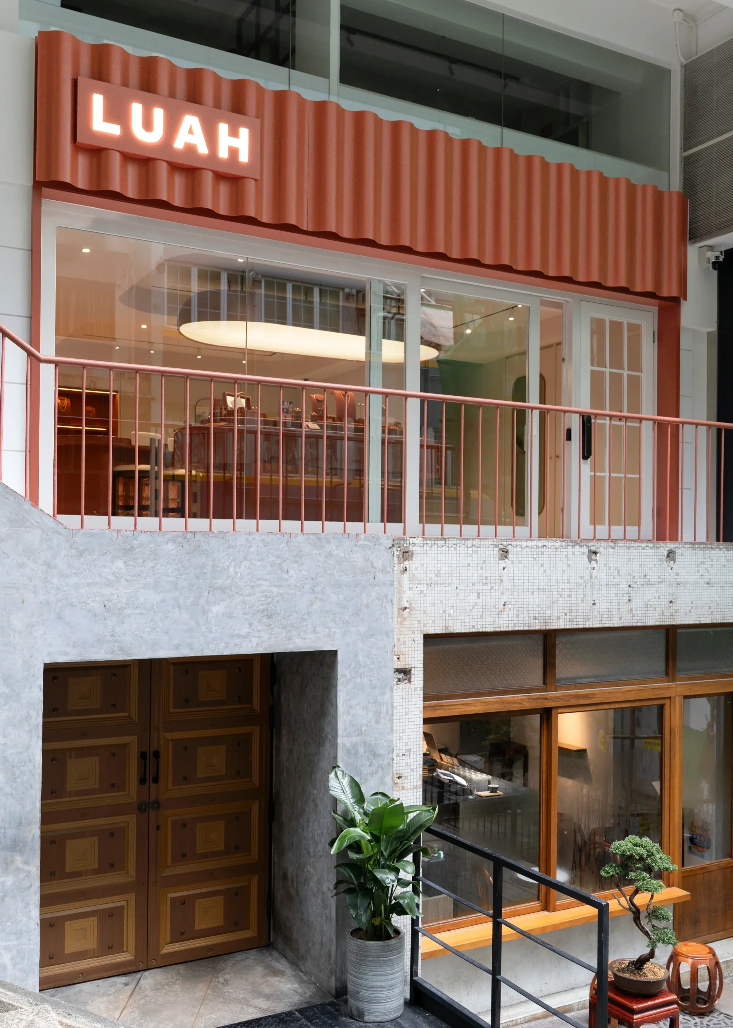 Shopfront design for LUAH at Shin Hing Street, Hong Kong, with corrugated terracotta cladding, full-height glazing and matching railings.