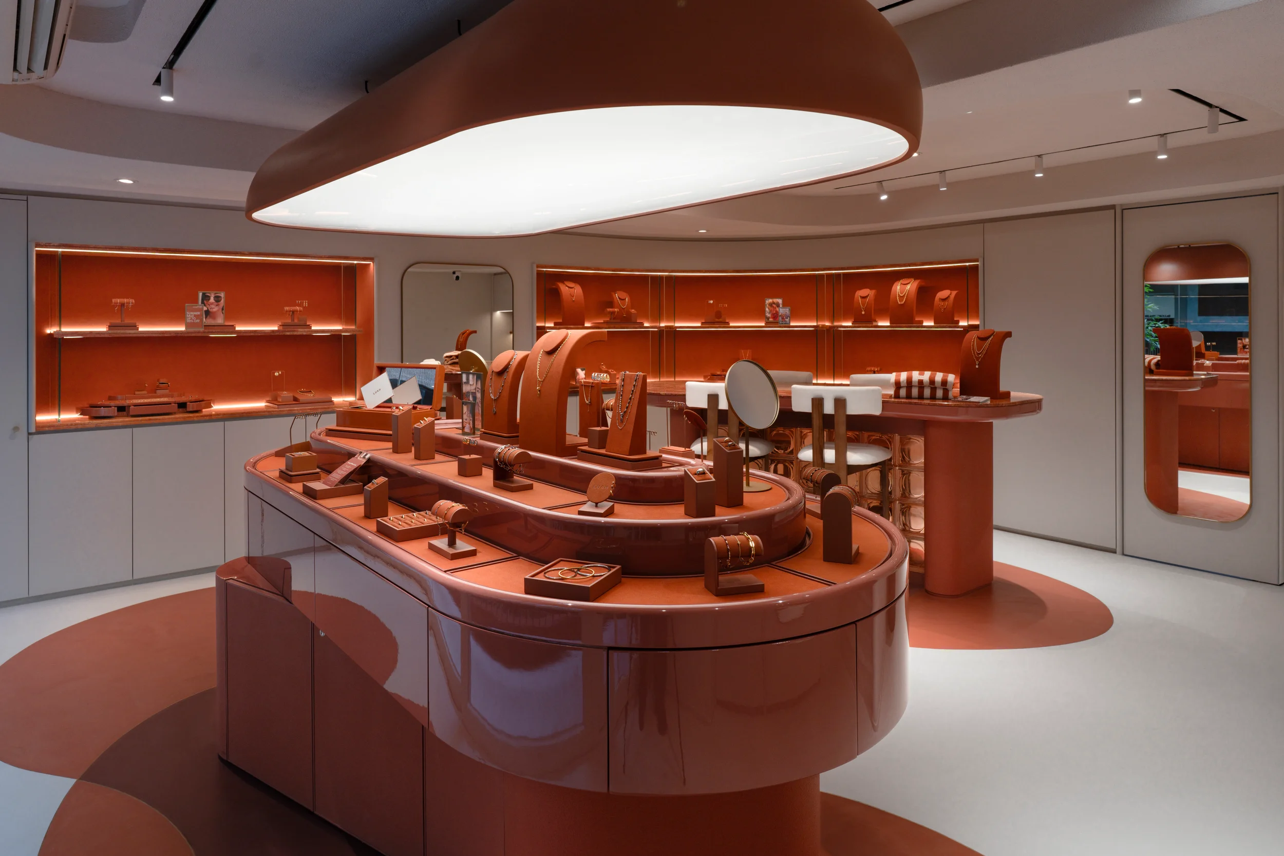 Jewellery store interior design for LUAH, Hong Kong, featuring a curved terracotta display island beneath a sculptural pendant light.