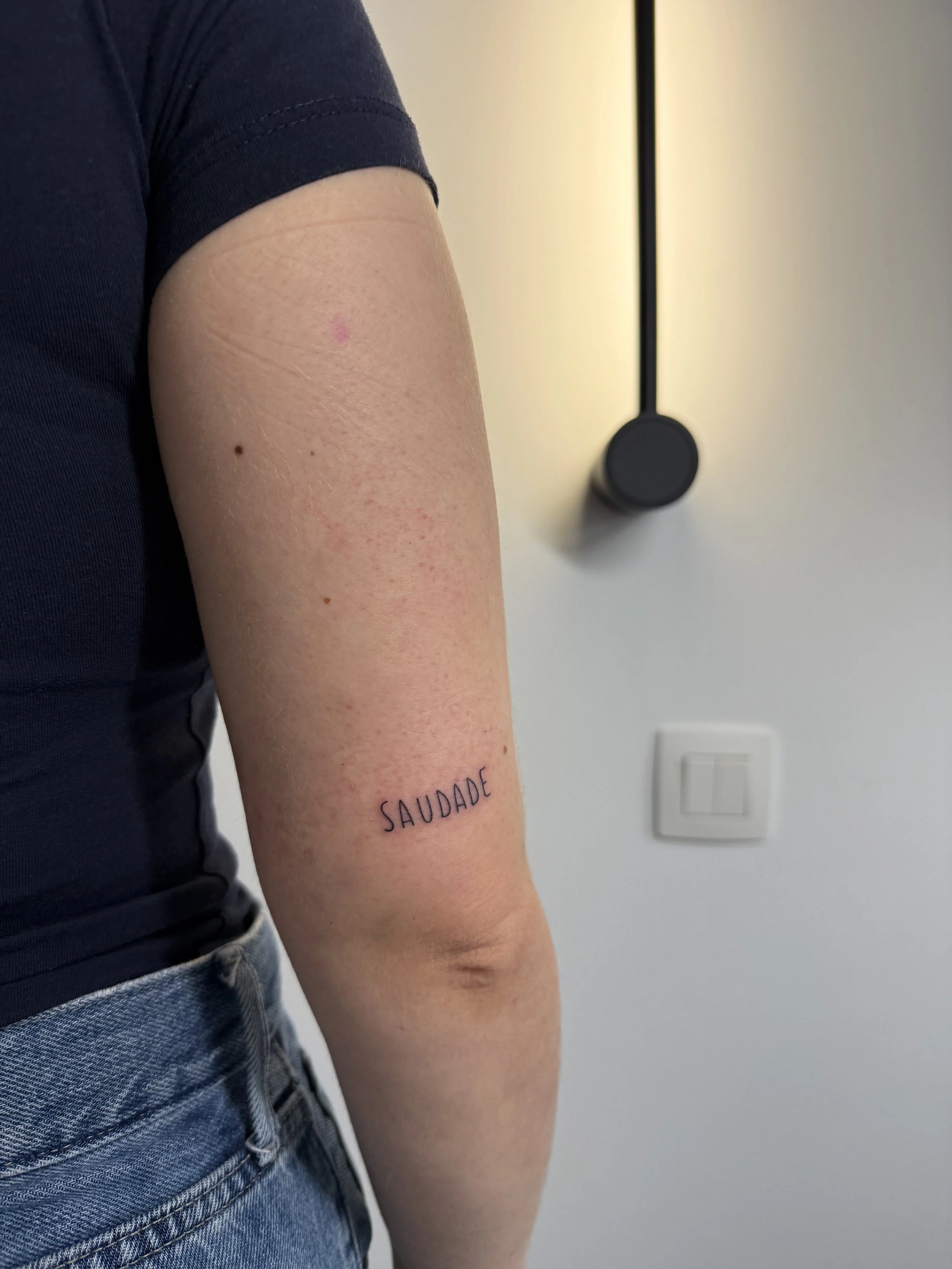 De onderarm van een persoon met de tekst 'SAUDADE' getatoeëerd.