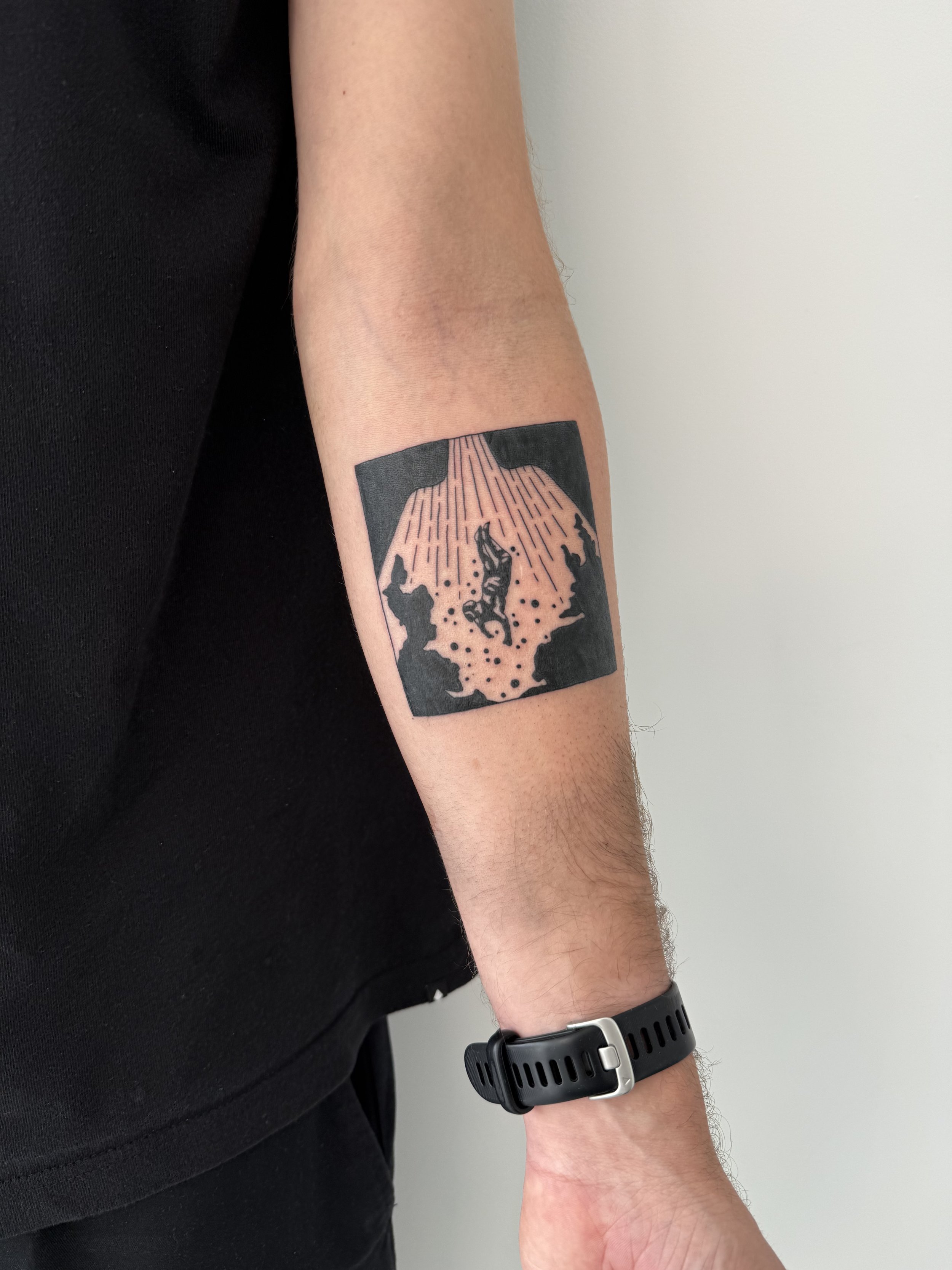 Een menselijke arm met een tatoeage van een persoon die onder een boom ligt, met stralen die naar beneden stralen.