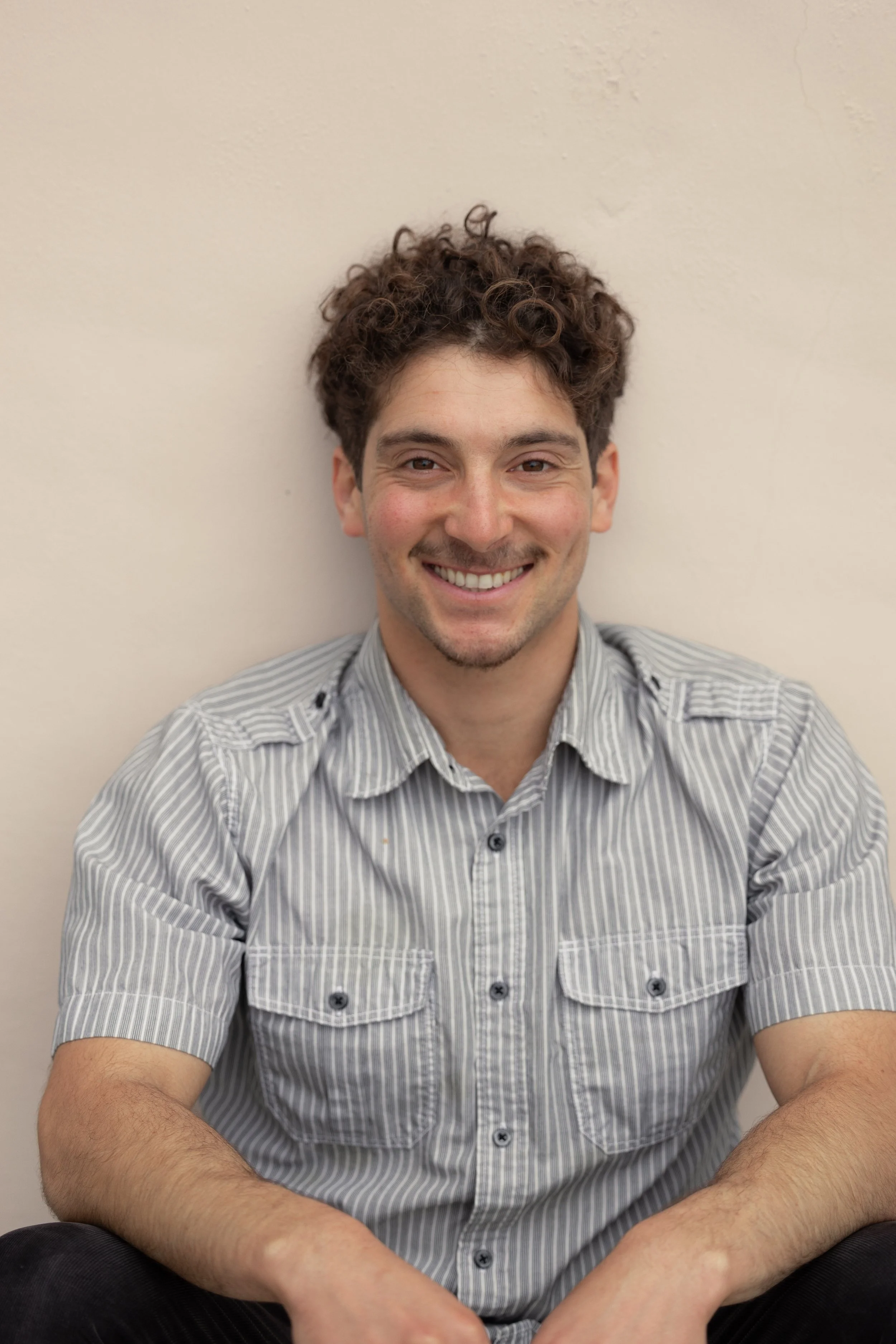 Smiling with a grey shirt on, our lead trainer Benny provides strength training for injury prevention and recovery from pain. His approach is a perfect match for people looking for osteoporosis strength training and biomechanics coaching.