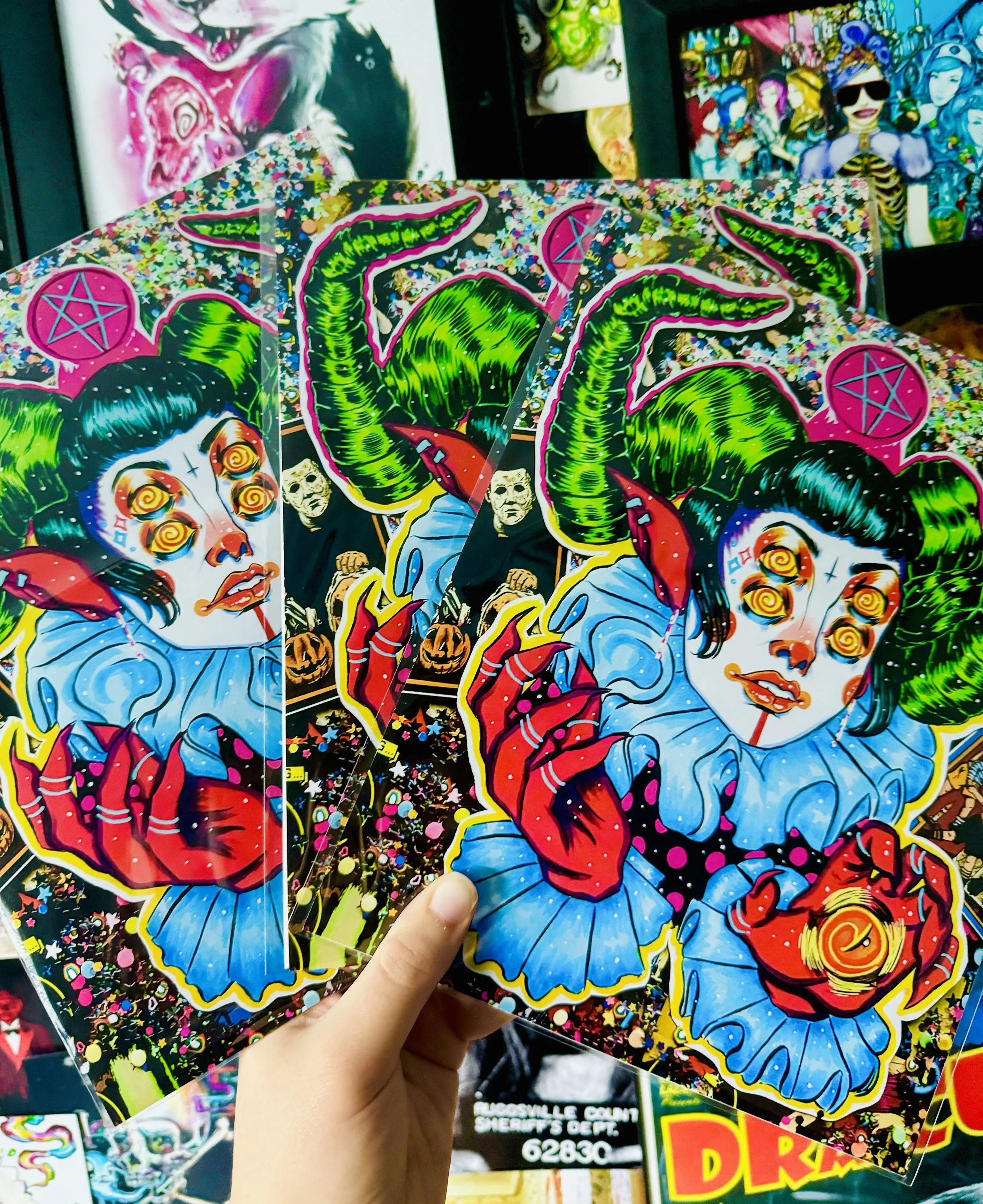 Colorful paper Halloween masks featuring a woman with green horns, a skeleton face, and other spooky designs, held in a person's hand at a store.