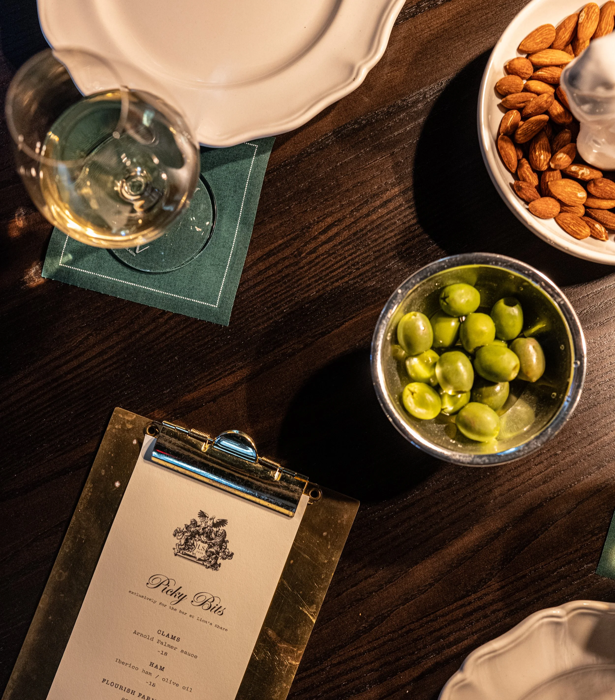 An overhead image of a spread of items and a cocktail from Lion's Share, along with logo'd menu