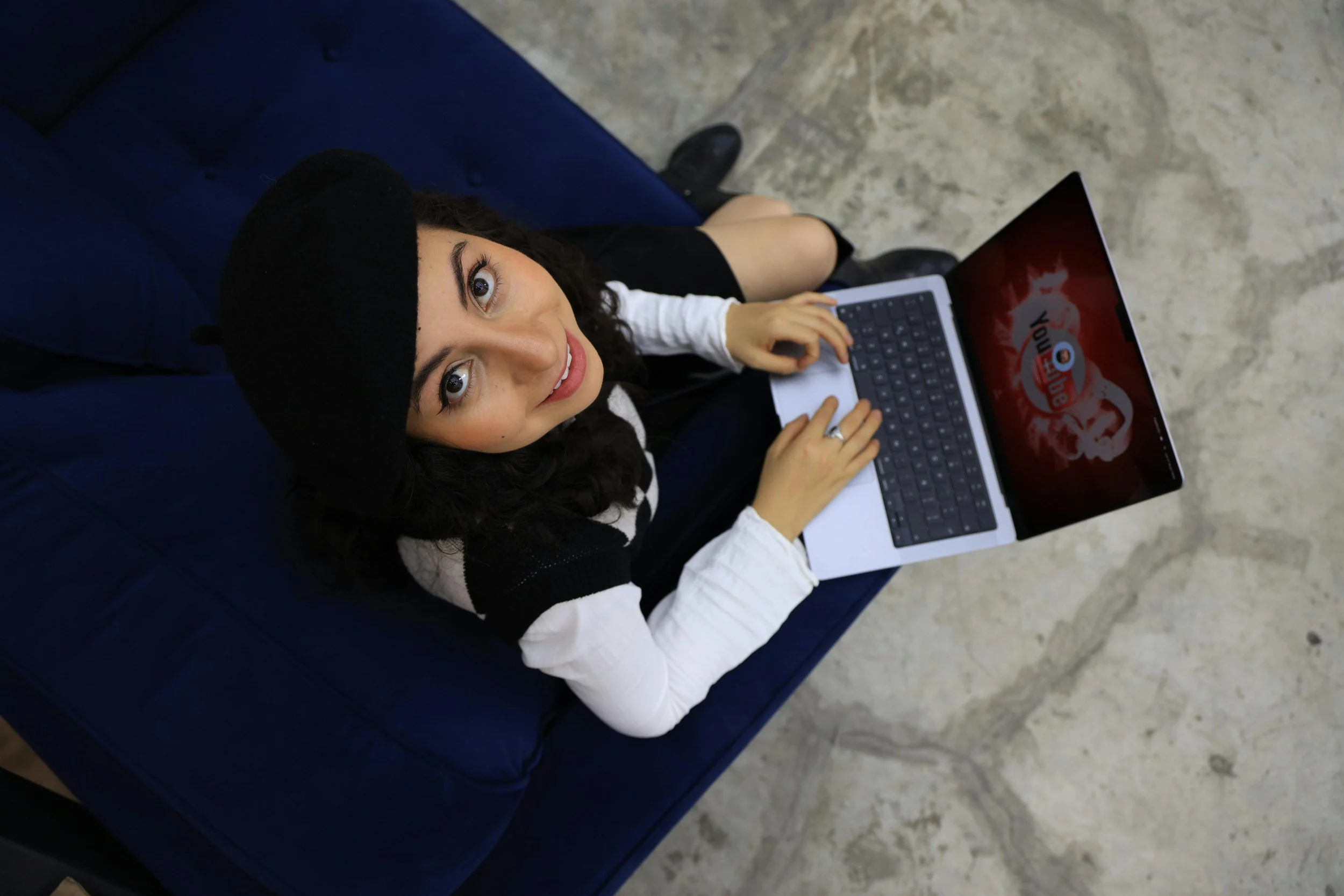 woman typing on laptop looking above her at camera