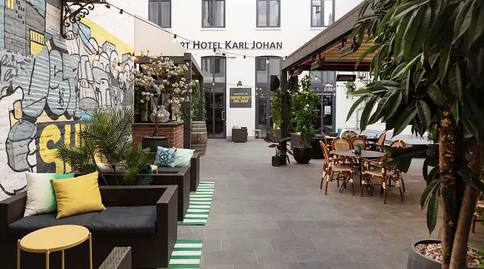 Outdoor patio with seating, graffiti on the wall, string lights, and plants at Smart Hotel Karl Johan.
