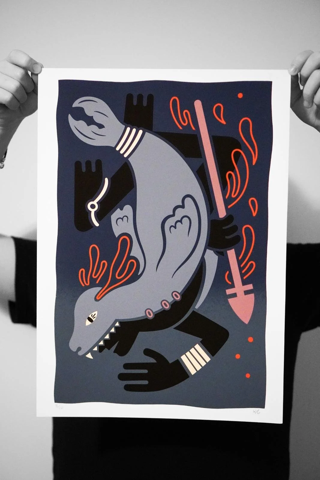 Person holding a colorful abstract illustration featuring a dragon, a hand with a wristwatch, an arrow, and fiery elements.