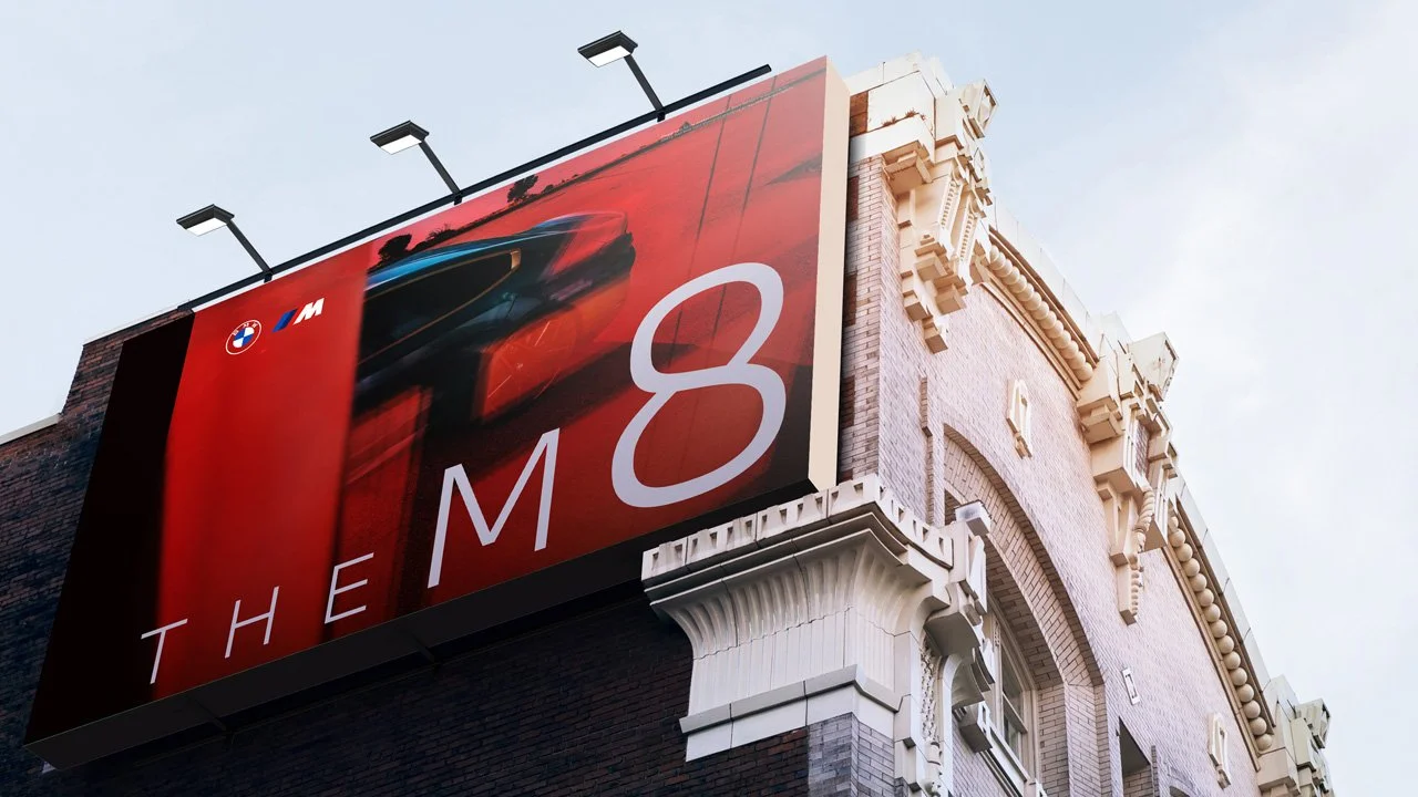Grande outdoor em um prédio anunciando o carro BMW M8 com fundo vermelho e uma imagem borrada do carro em movimento.