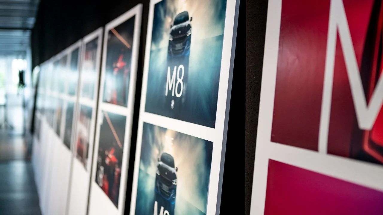 Fotografias de um modelo de carro exibido em uma parede de uma exposição ou galeria.