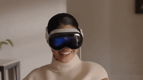 A woman laughing while wearing a virtual reality headset in an indoor setting.