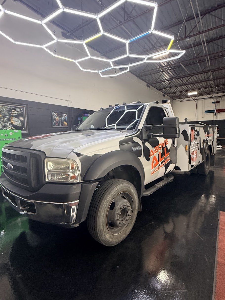 A Black and gray rescue fire truck parked indoors under a decorative hexagonal LED light fixture custom printed vinyl and graphic design near denver colorado