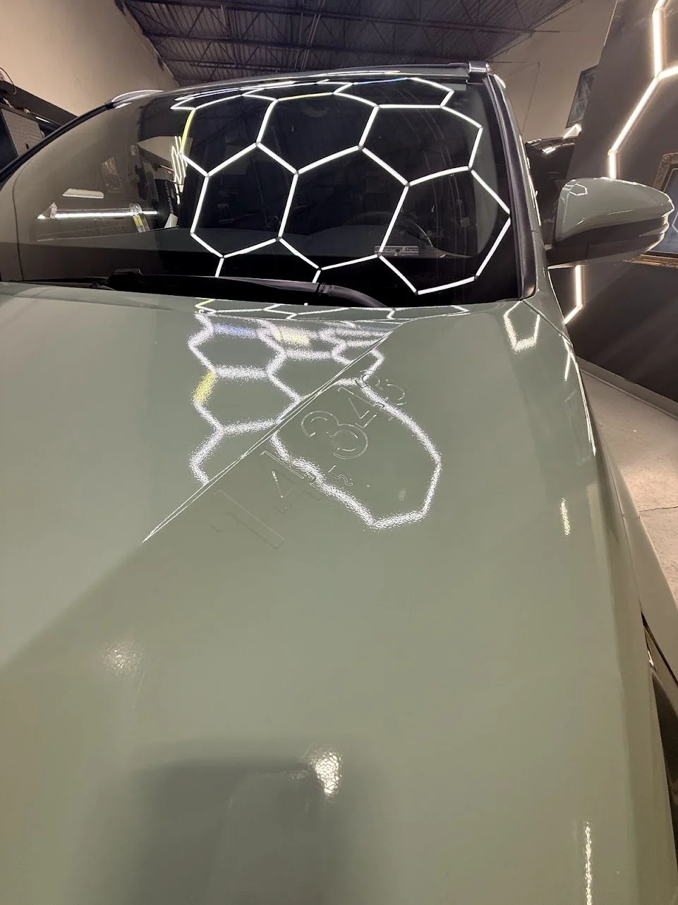 A green car with a geometric LED light pattern on the dashboard and a galaxy-shaped LED design on the windshield.