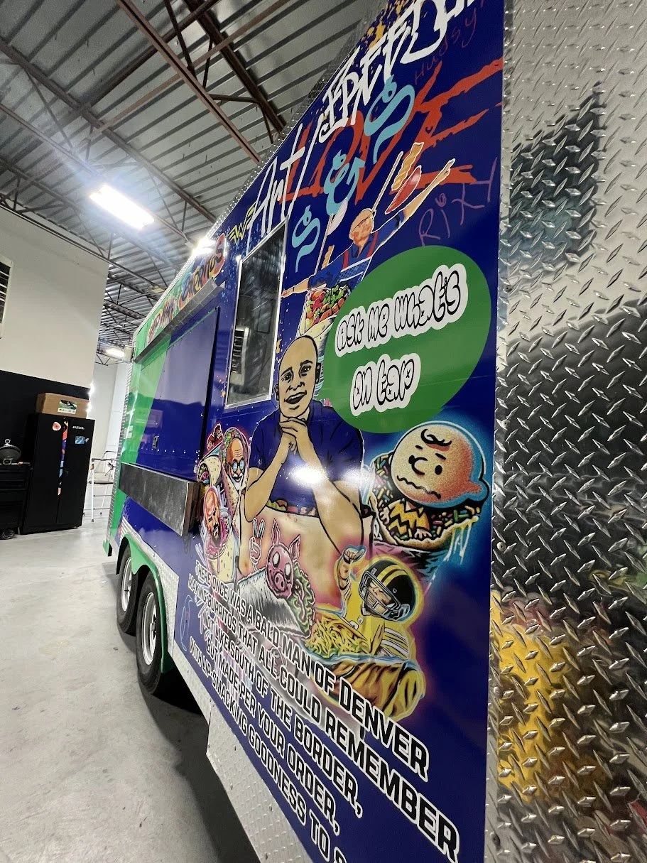 Colorful mural on the side of a vehicle featuring cartoon characters, a person, and graffiti-style art with text reading 'Ask me where I come from.'