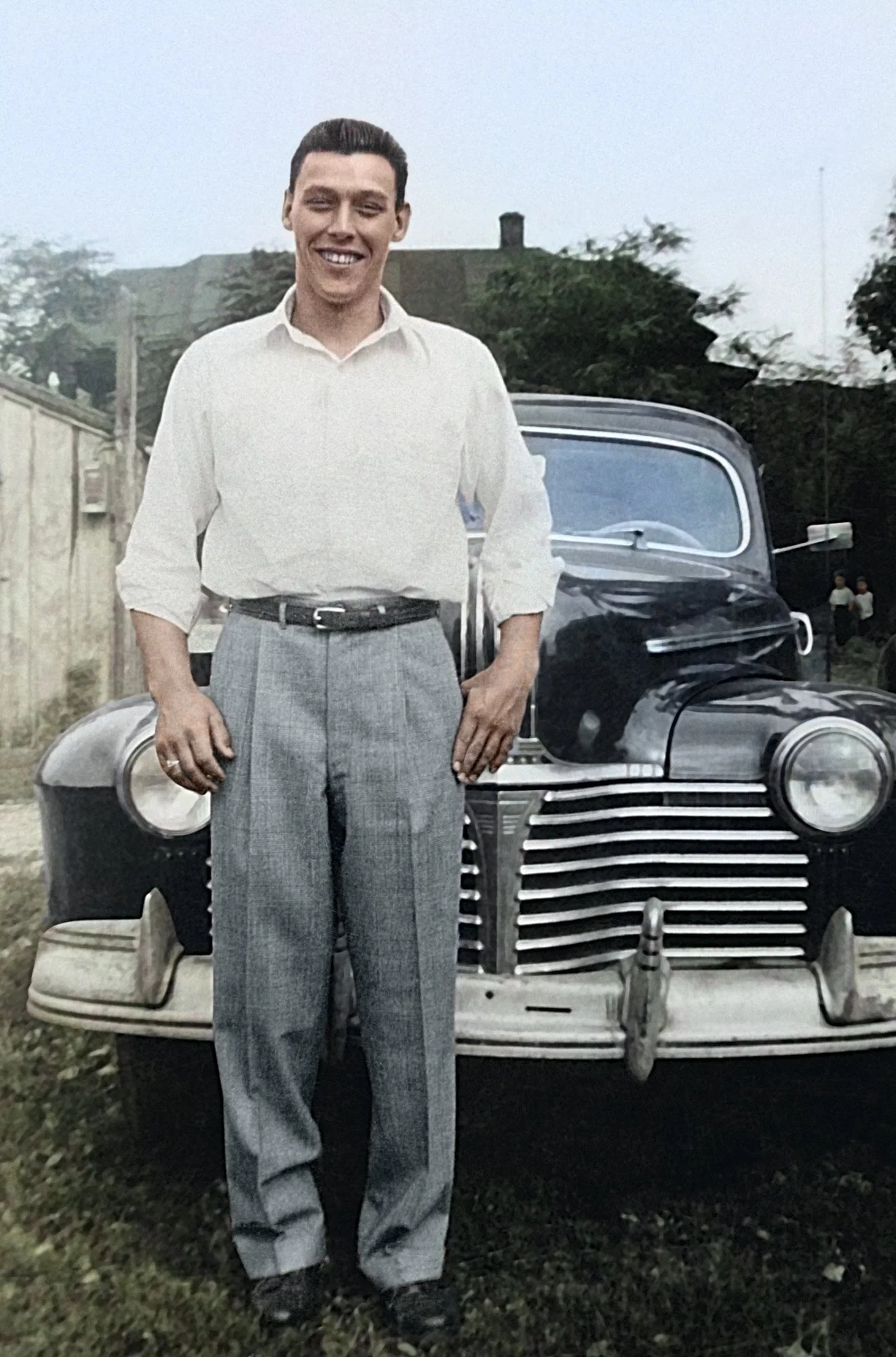 Colorized photo of Bob Travis standing in front of Jack Kosila’s car (late 1940s)