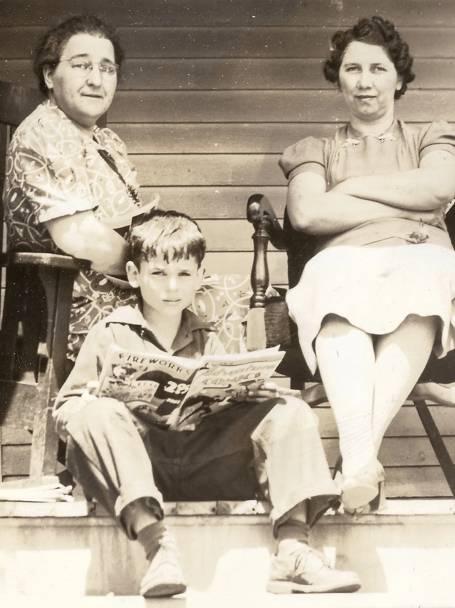 Bill is relaxing on the porch, enjoying the latest issue of his favorite comic. Tilly, his mother, and a neighbor are also there, sharing the peaceful moment.