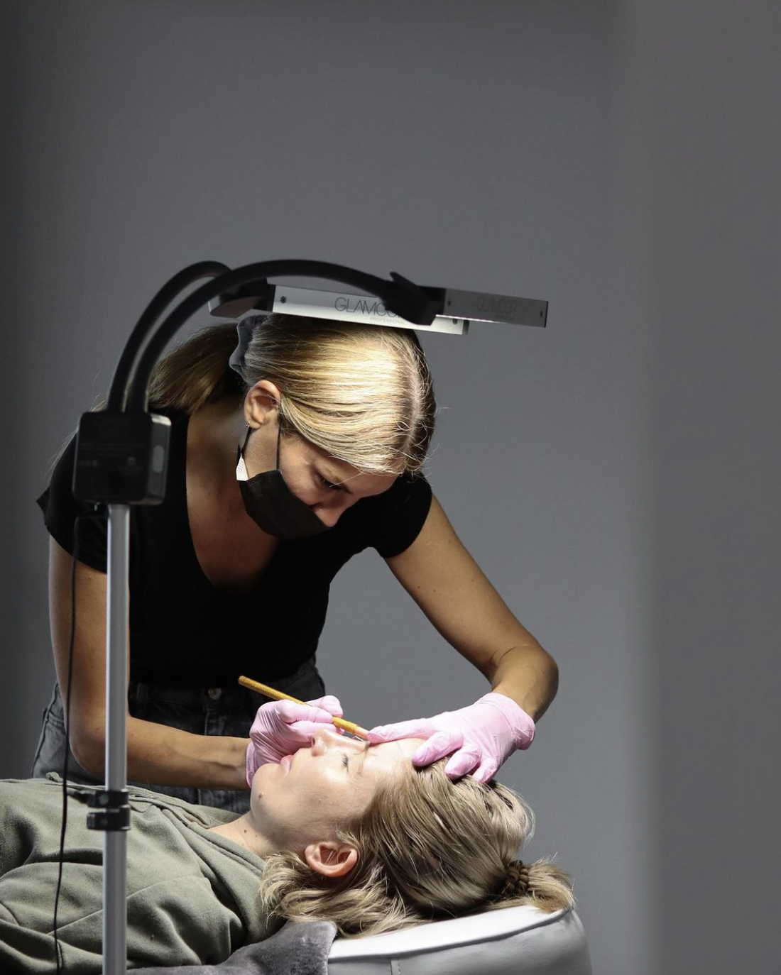 Woman brushing her brows at KAD Brows – professional brow lamination, NanoBrows, ComboBrows, and brow shaping in Montreal.