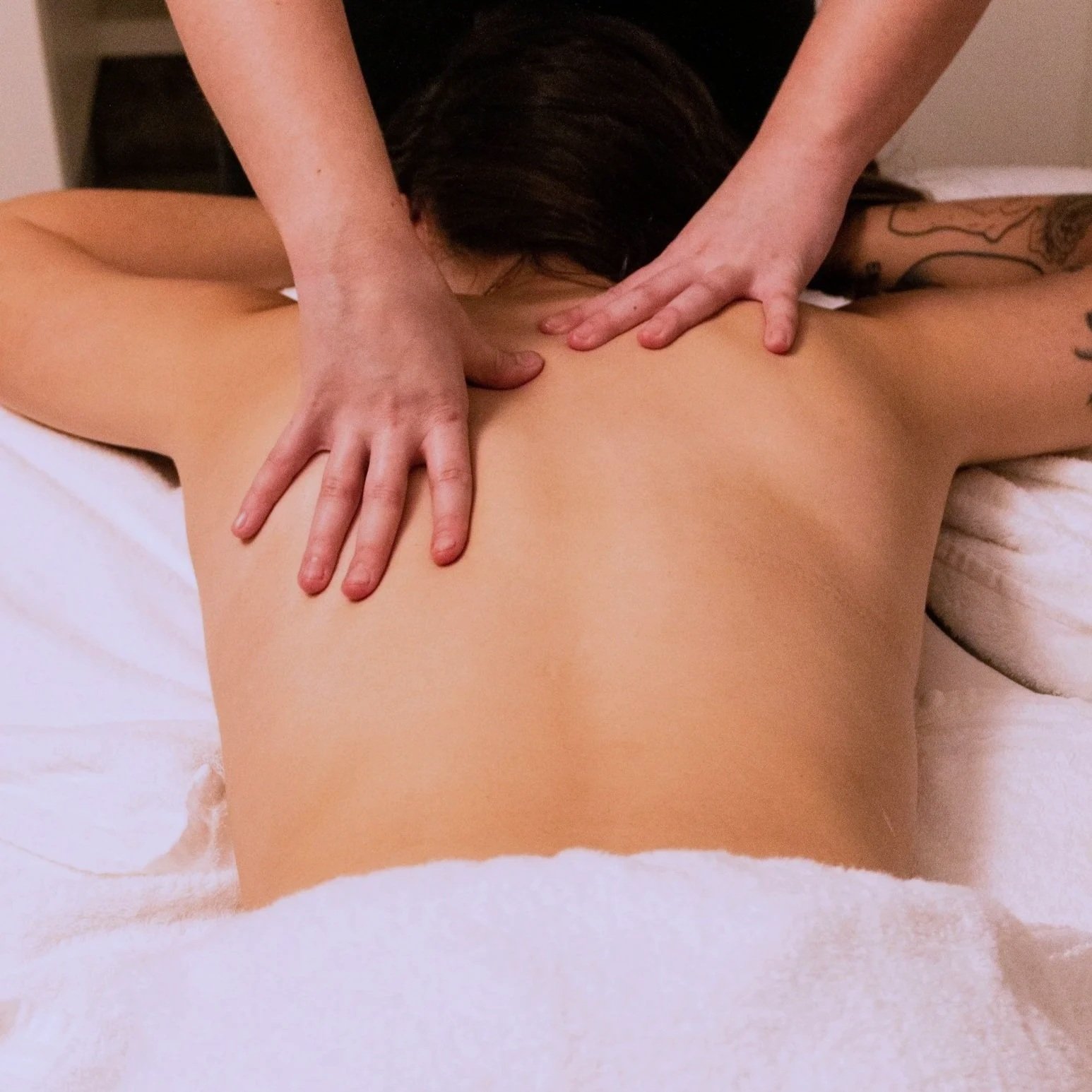 Person receiving a back massage on their bare back from a massage therapist.