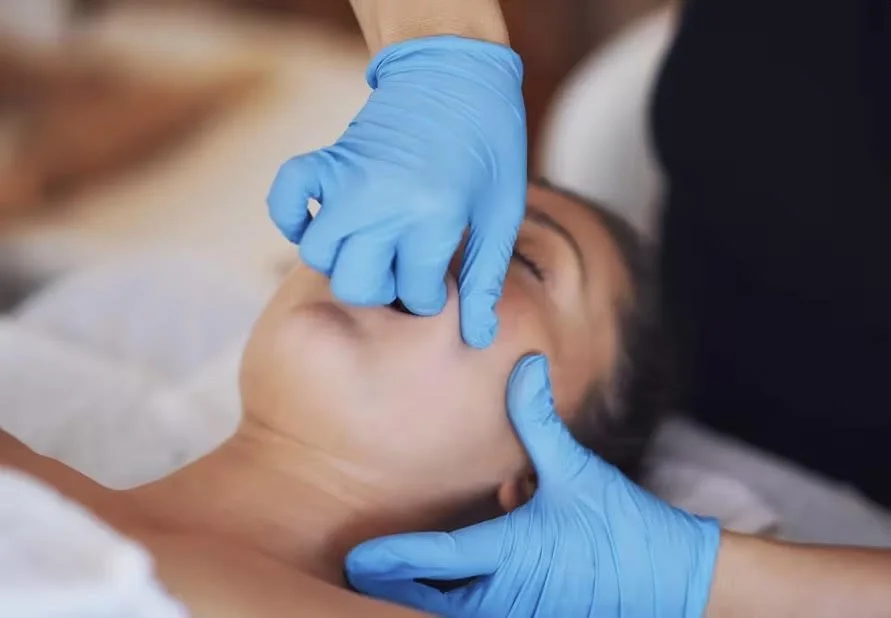 Intraoral Massage Therapist professional performing manual therapy on a patient's neck with gloved hands.
