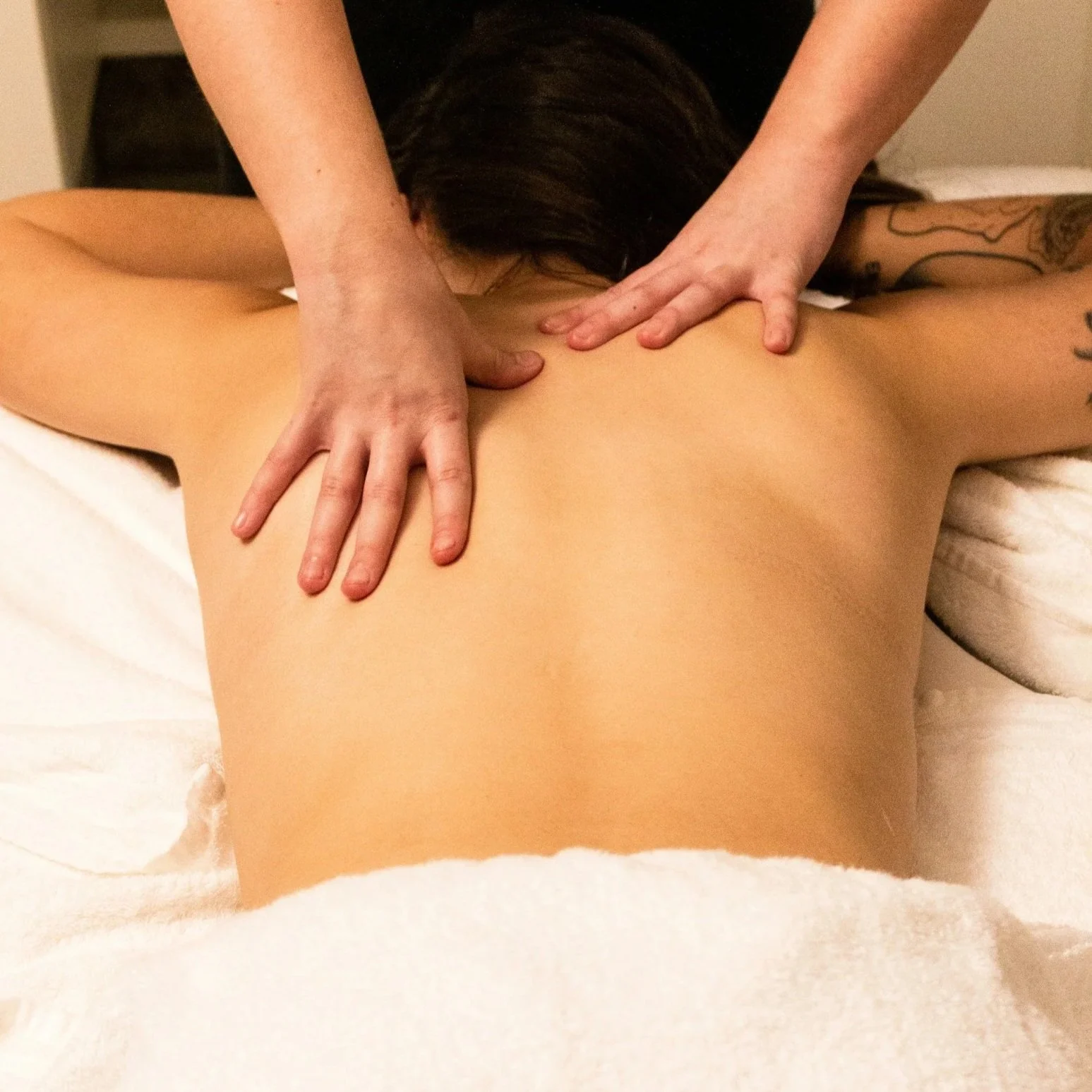 Person receiving a back massage on their bare back from a massage therapist.