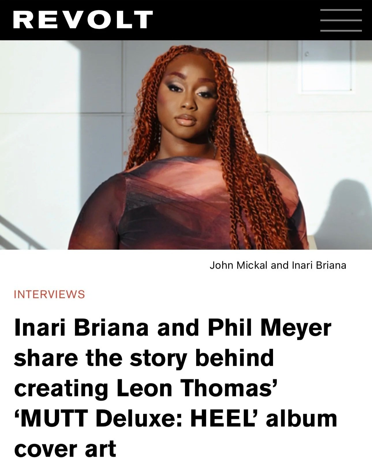 A woman with long, curly, orange hair and wearing a colorful, patterned top, standing against a light background with shadow.