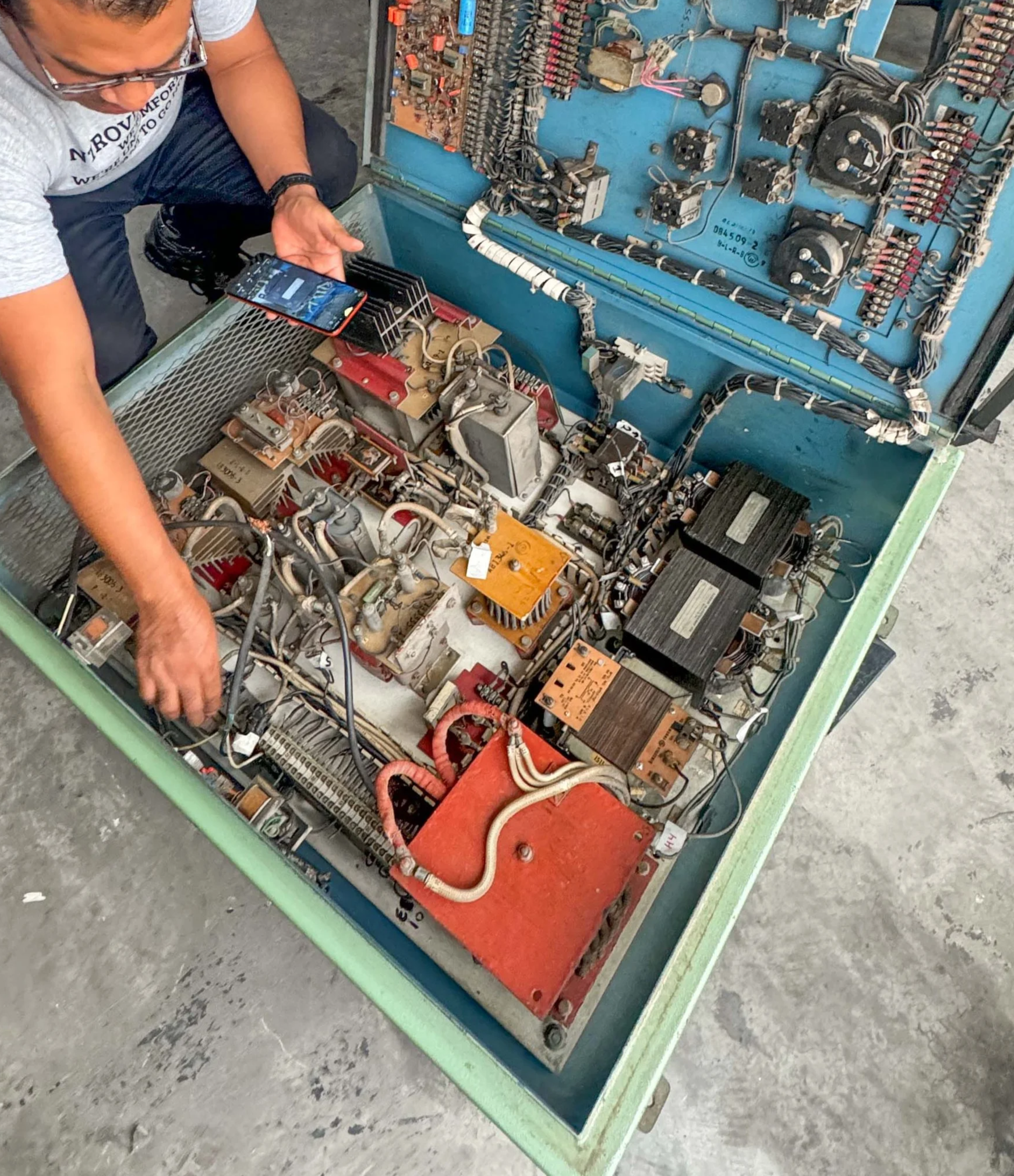 Persona inspeccionando componentes electrónicos en un equipo de alta tensión.»