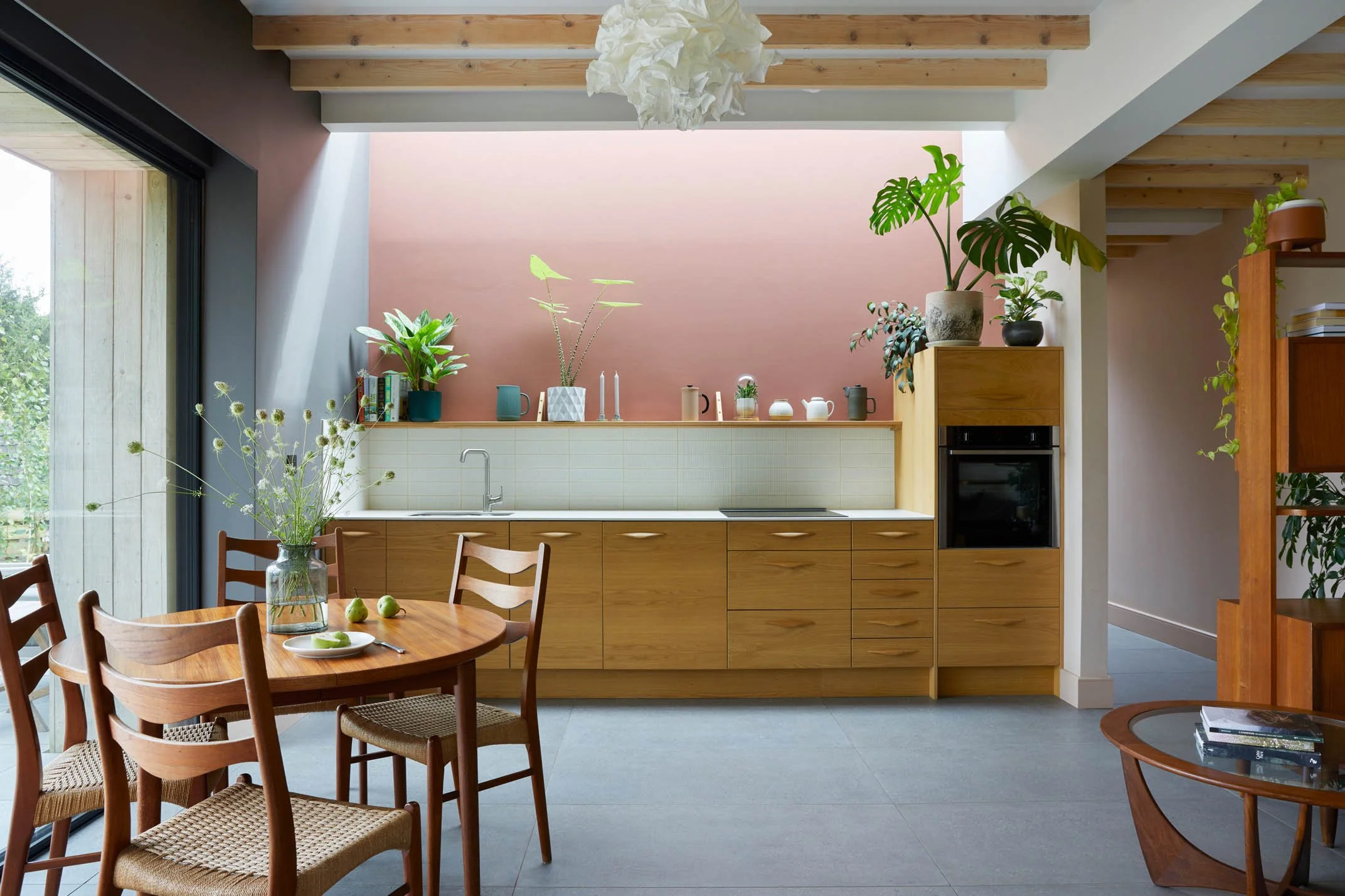 Minimal kitchen-diner with wide glazing framing the surrounding woodland.