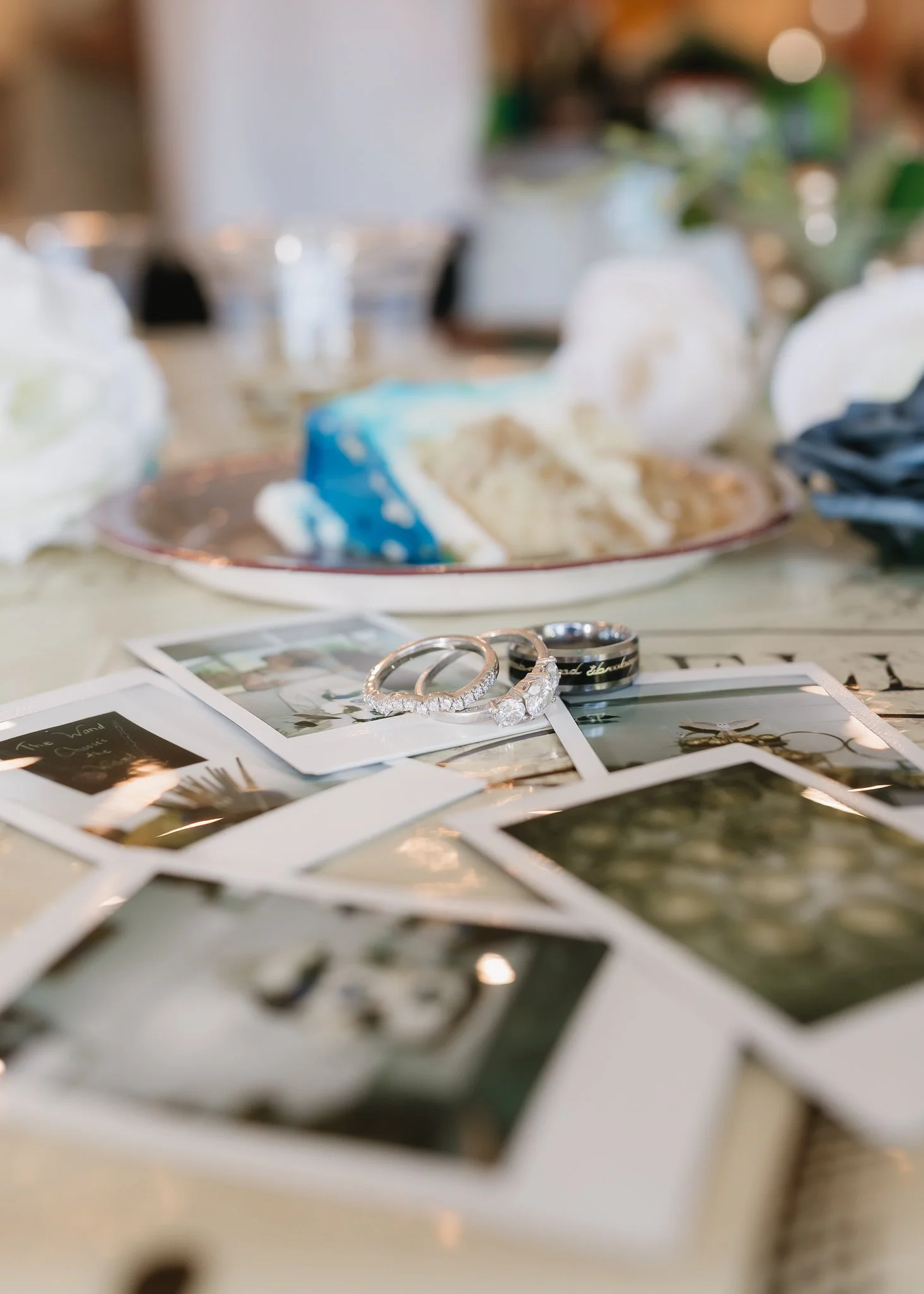 Wedding rings and photographs on a table with a slice of cake in the background.