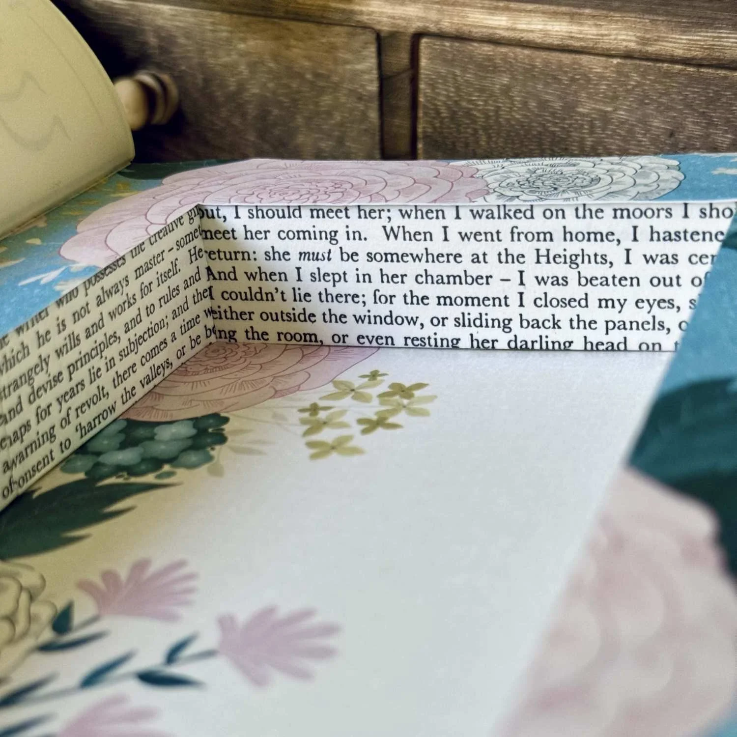 A close-up view of the secret compartment in a hollow book box, featuring floral paper and book text.