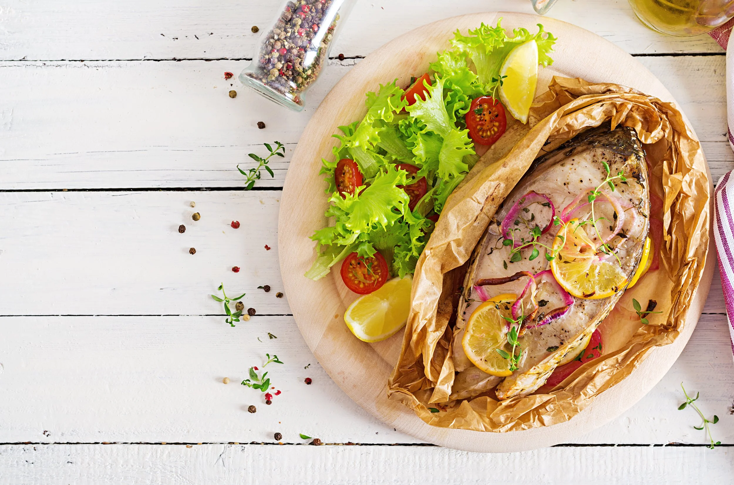 Fresh fish with parsley, lemon slices, onion and spices prepared for baking on parchment paper