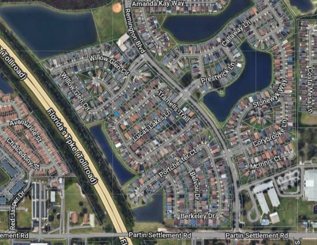Aerial view of a residential neighborhood with lakes, streets, and a highway.