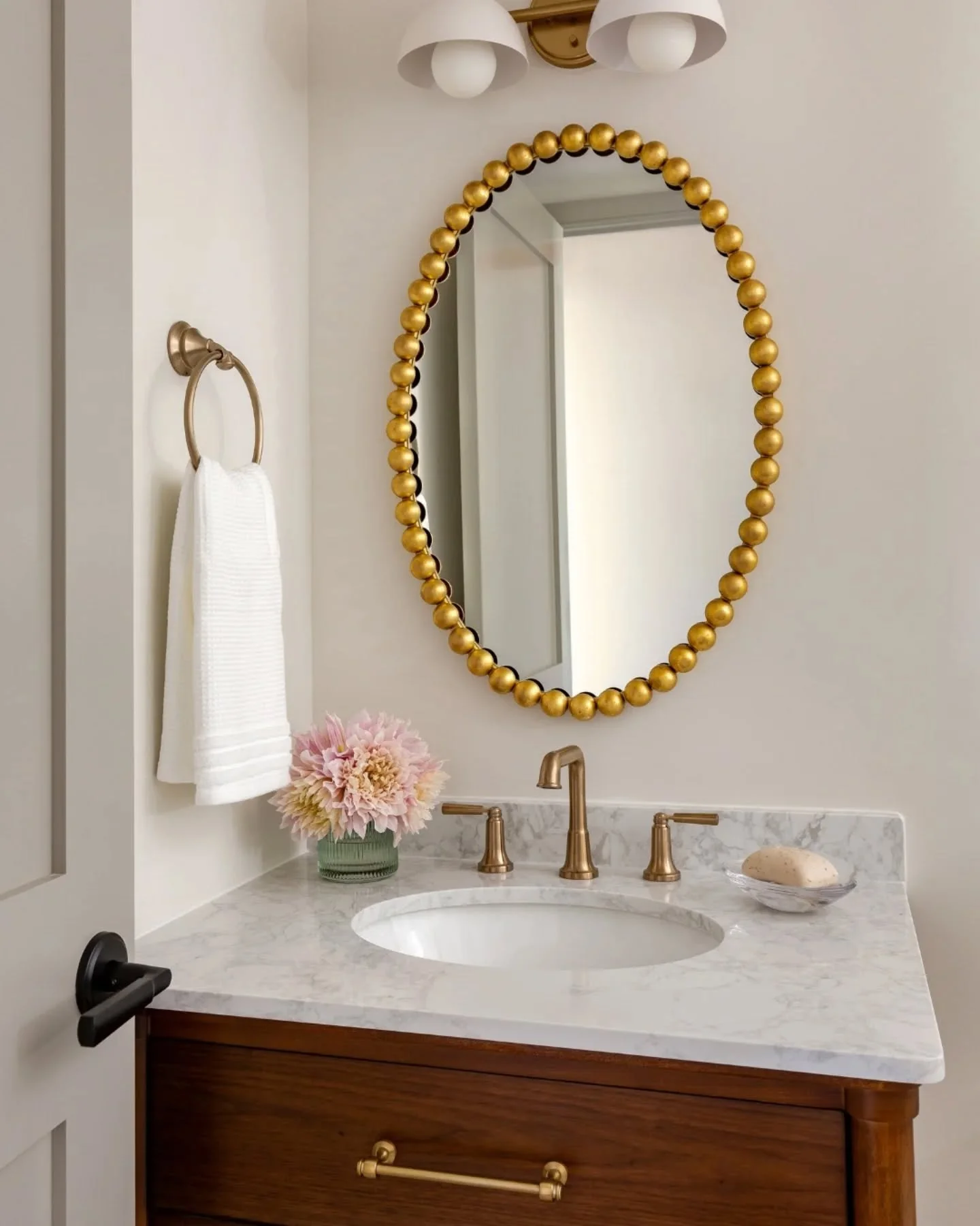 Clean, simple, and soft lines in this full bathroom from my North Potomac Cottage project. I love the rounded edges of the vanity and its furniture-inspired design. The gold bobbin oval mirror adds a playful touch. Located just off the main living ar