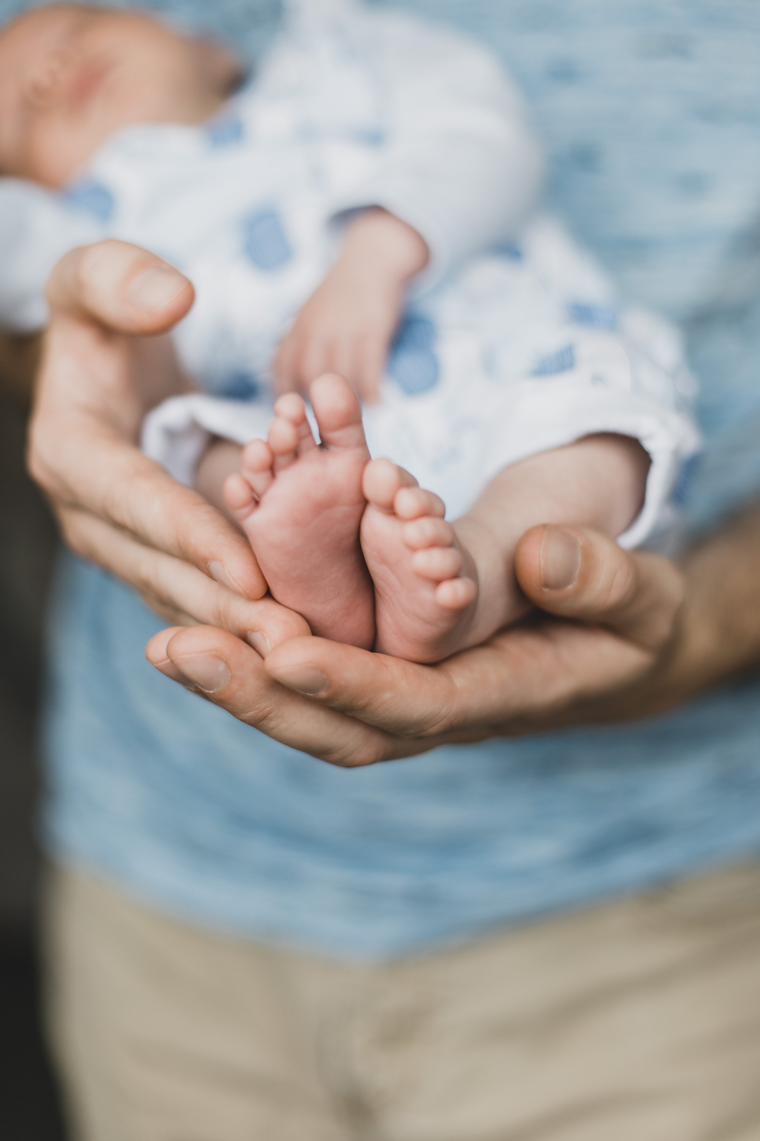 Close-up of baby's feet held in adult's hands