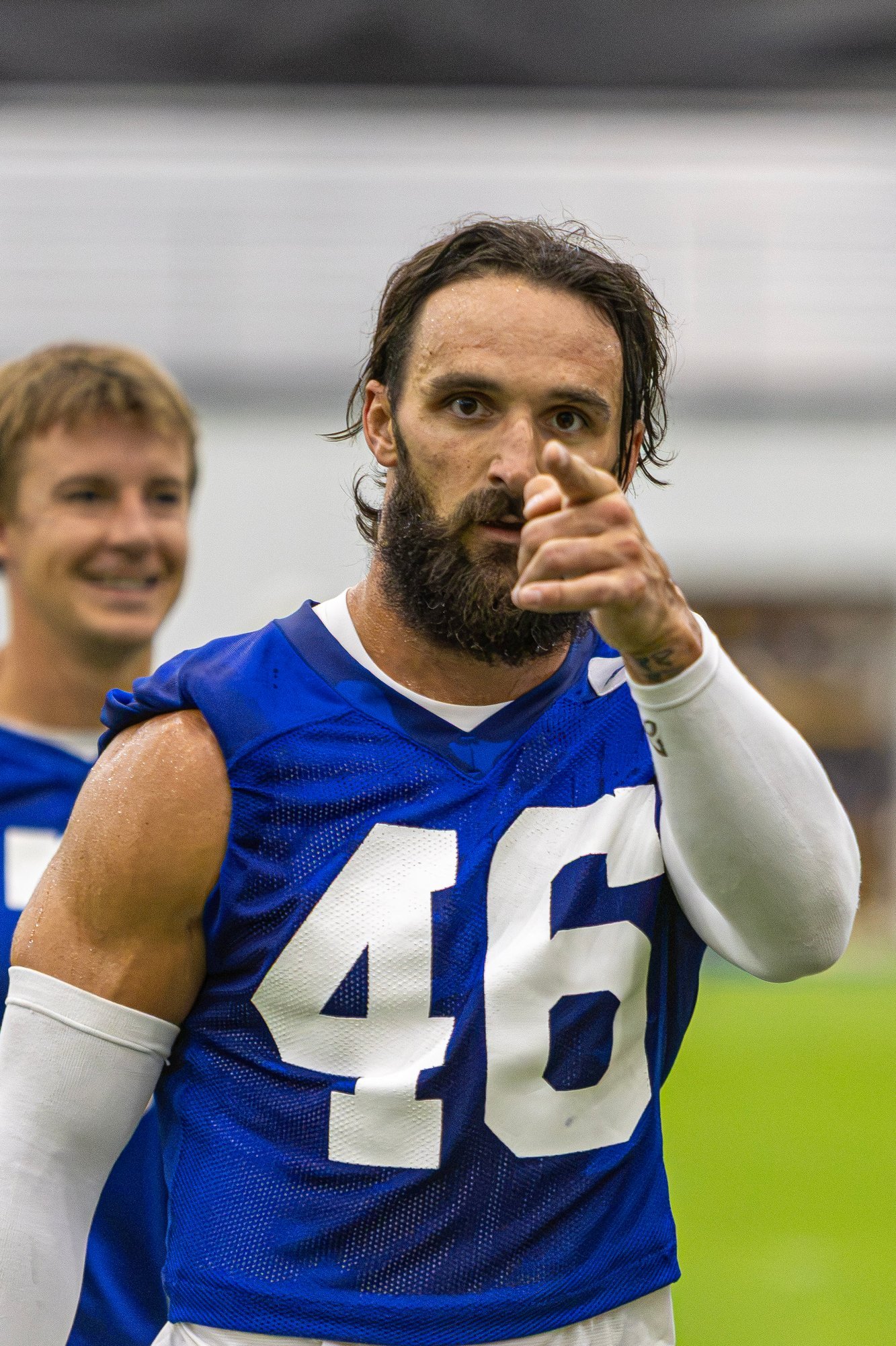 Colts player in a blue practice jersey pointing and smiling during training camp.