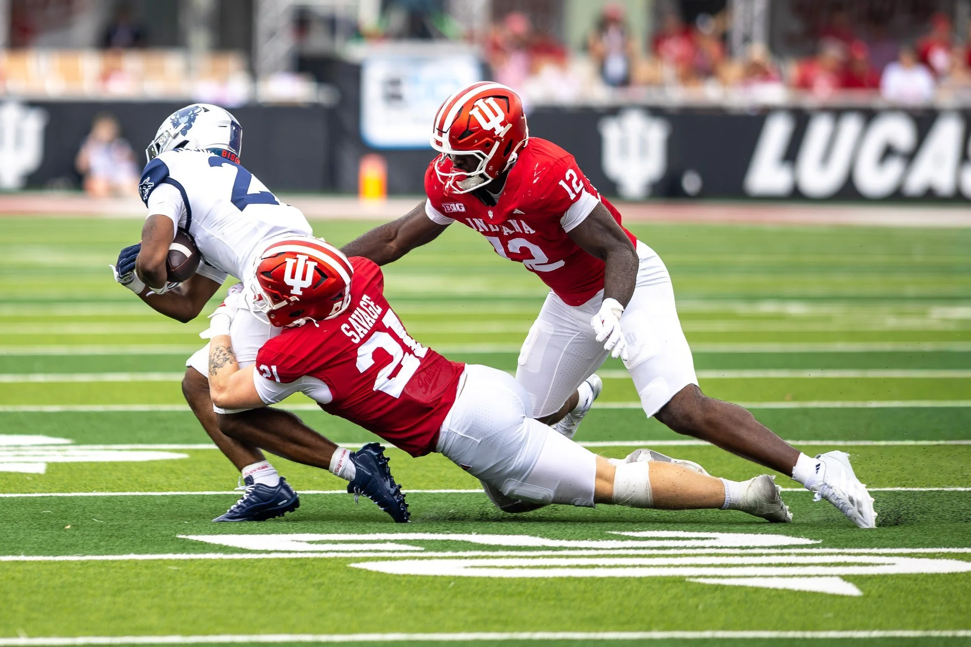 Indiana defenders bringing down an opposing ball carrier on the field.