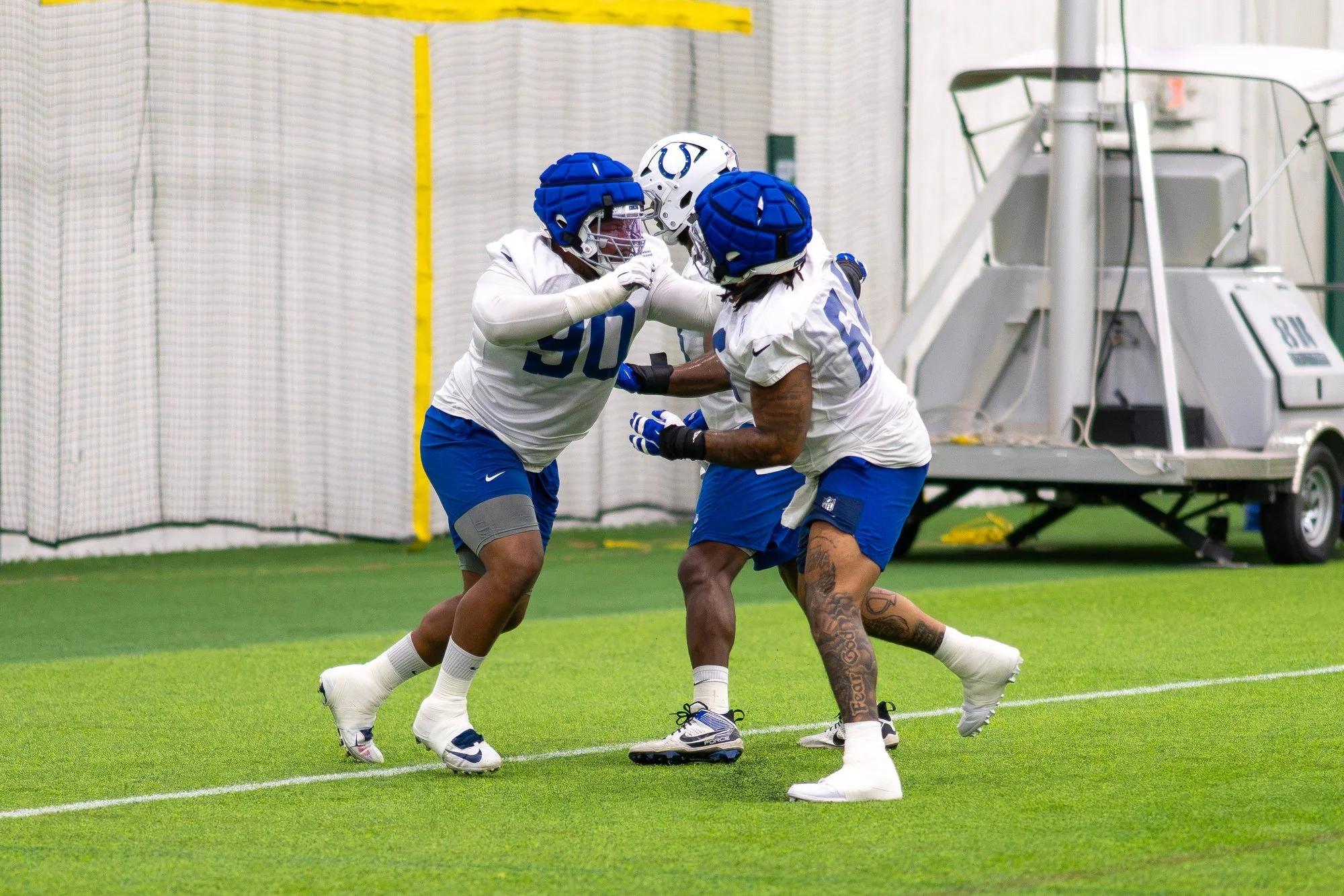 Two Colts linemen engaging in a blocking drill on the indoor practice field.