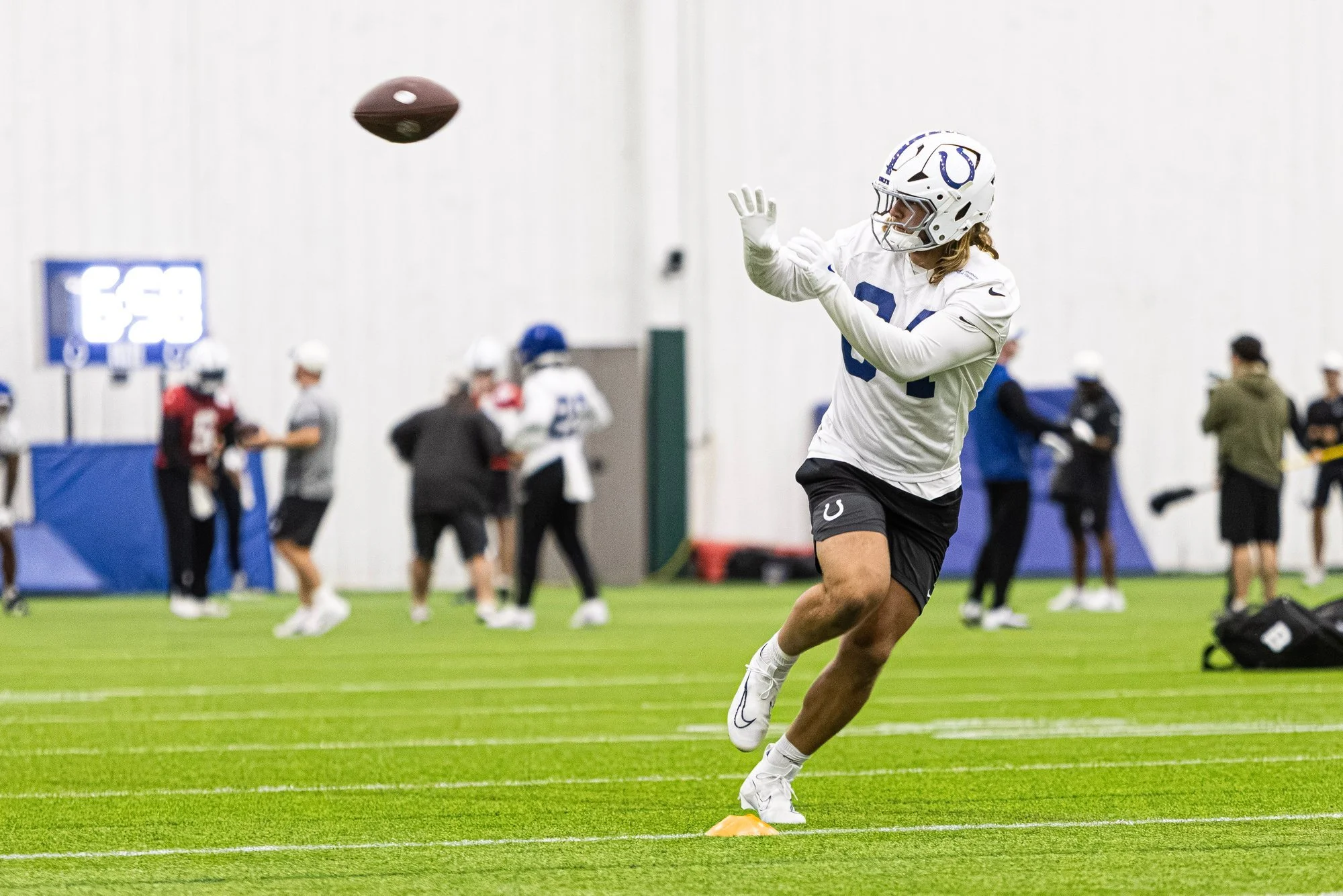 Colts receiver tracking a pass in the air during an indoor training camp drill.