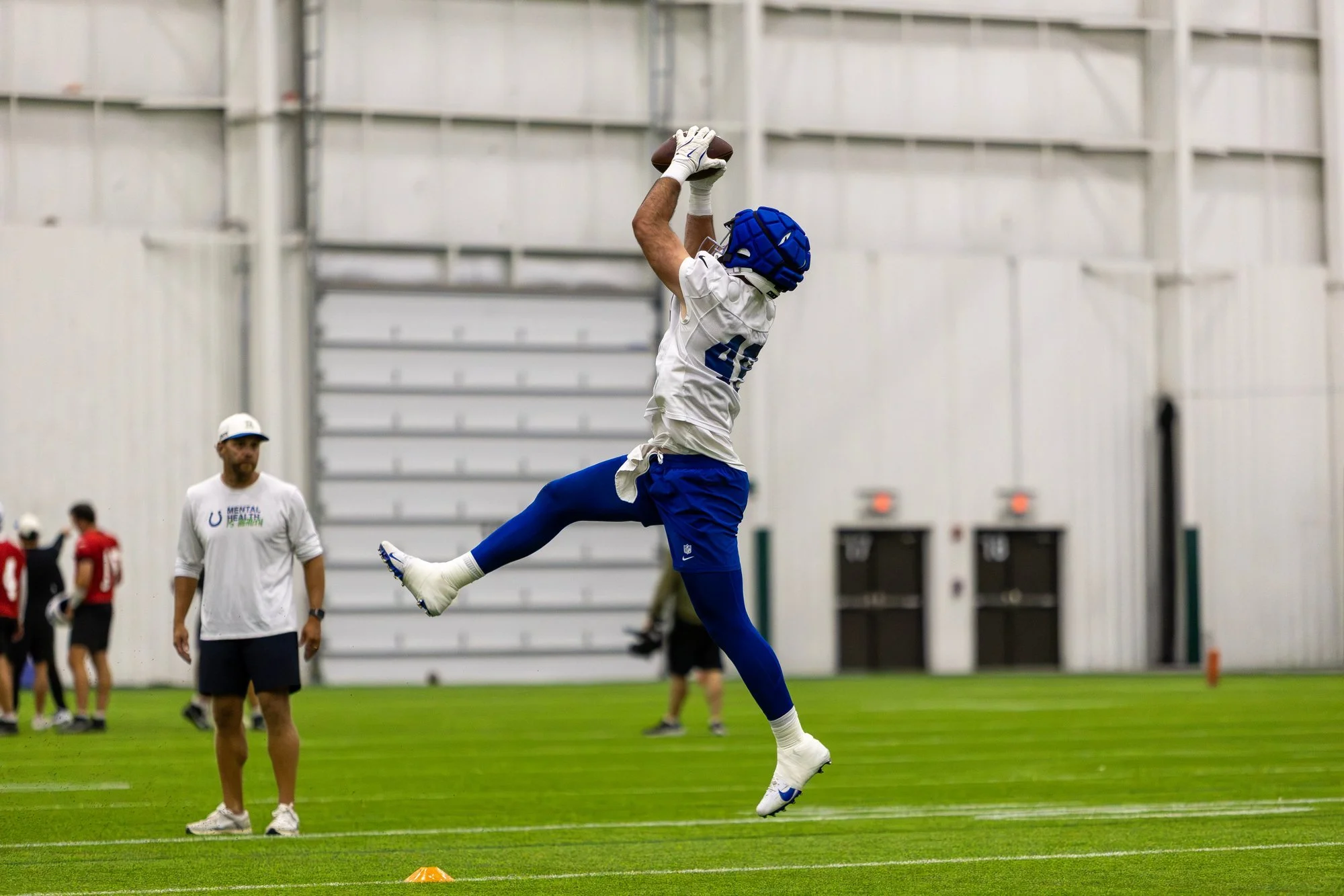 Colts receiver leaping high to make a catch inside the indoor practice facility.