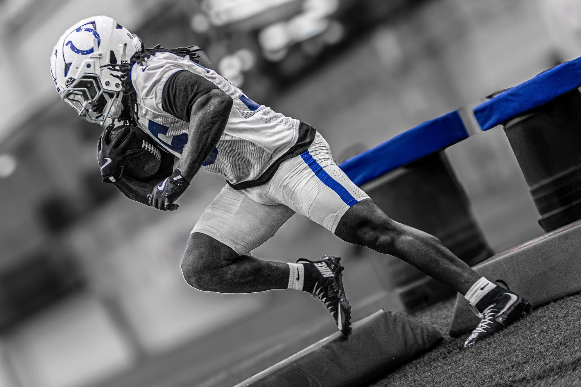 Black-and-white image of a Colts player driving low through a practice drill.