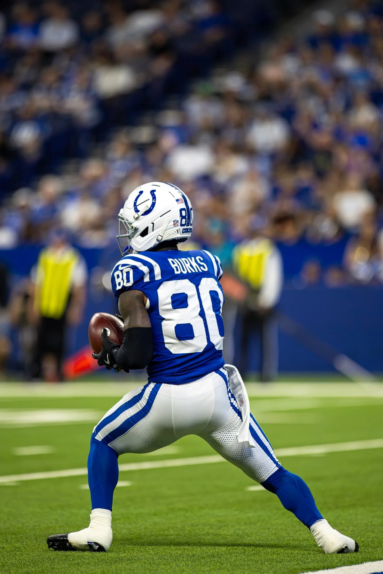 Indianapolis Colts receiver in a blue jersey securing the football after a catch near the sideline.