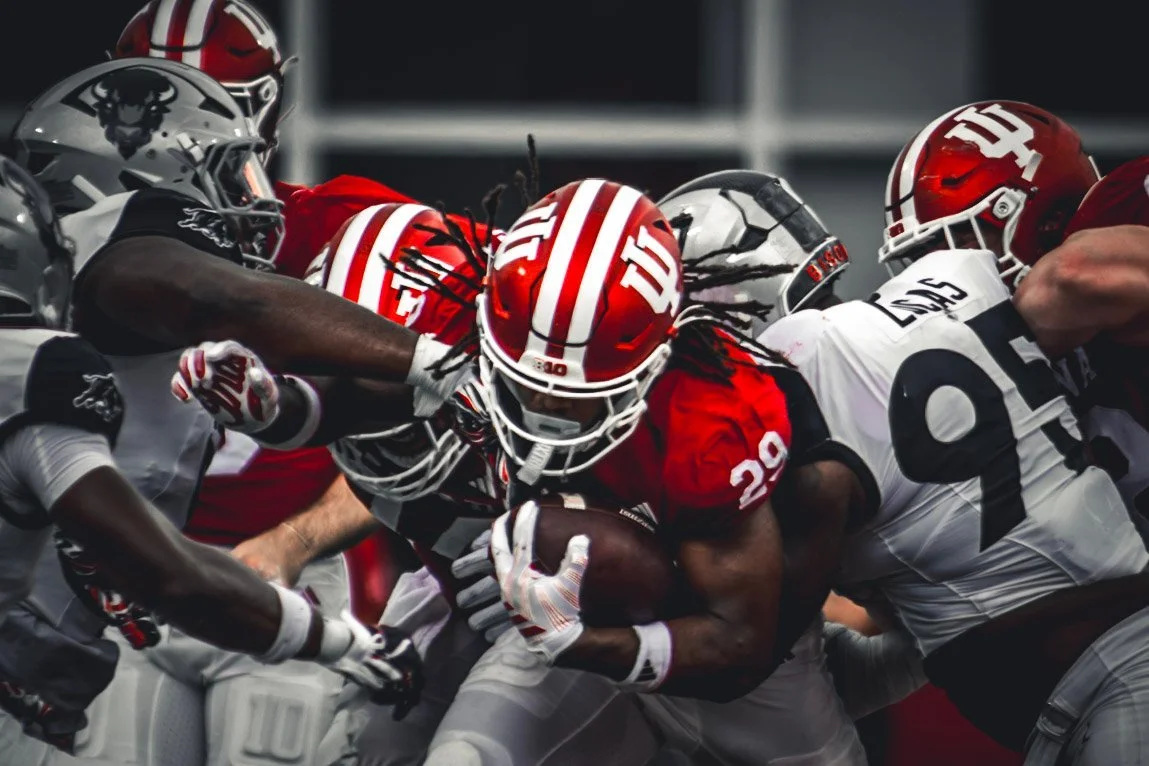 Indiana ball carrier pushing through a crowd of defenders.