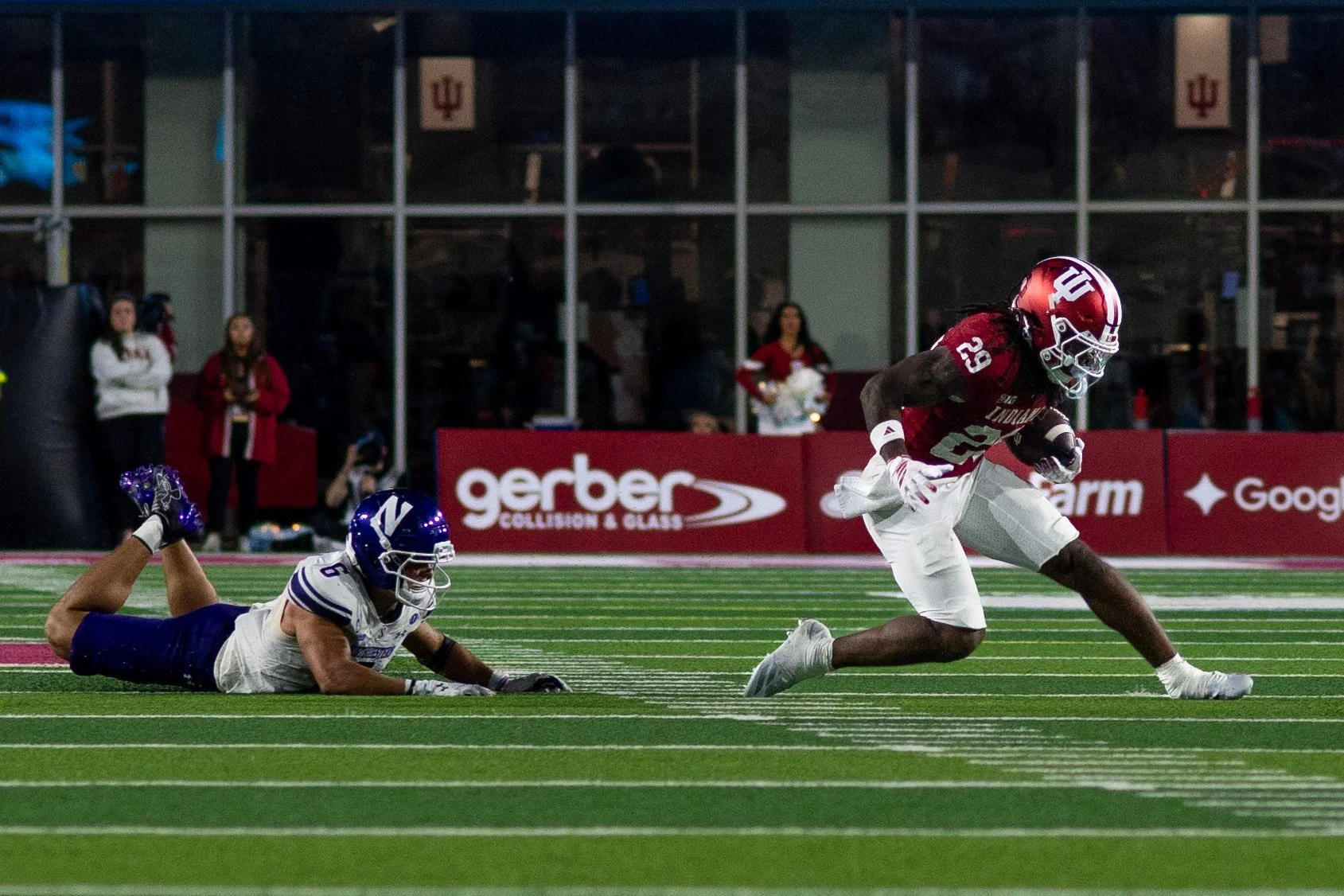 Indiana ball carrier running past a fallen Northwestern defender.