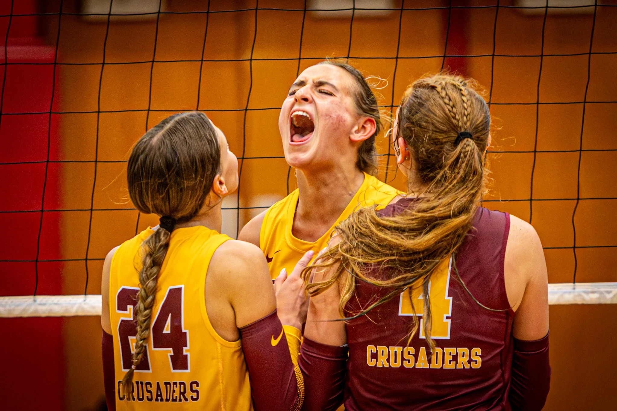 Crusaders volleyball players celebrate a point at the net