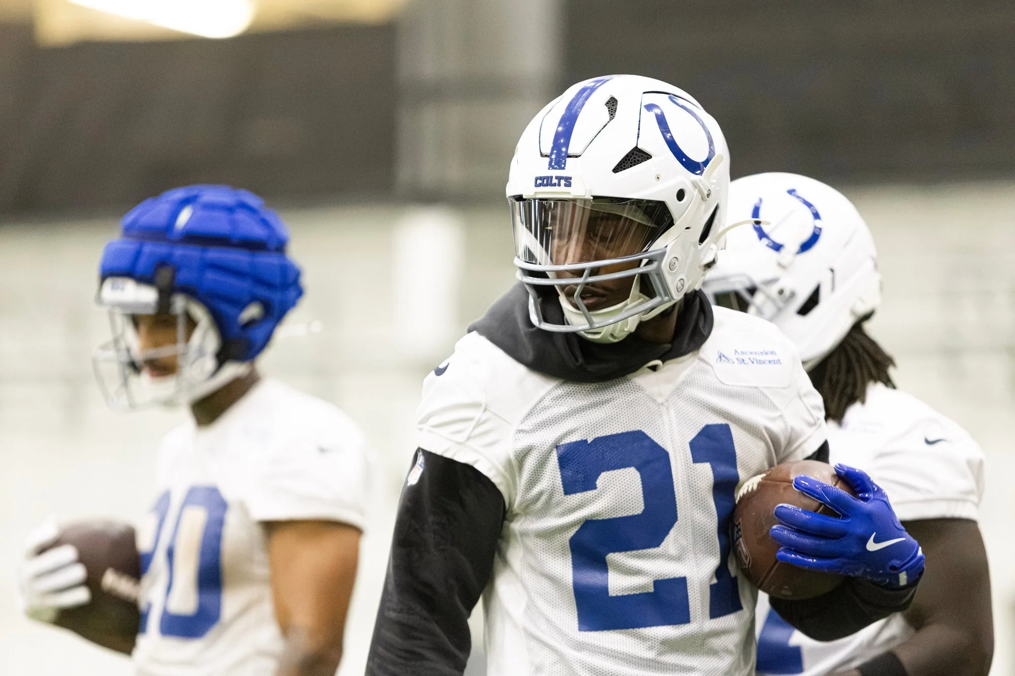 Colts running back carrying the football during an indoor training camp drill.