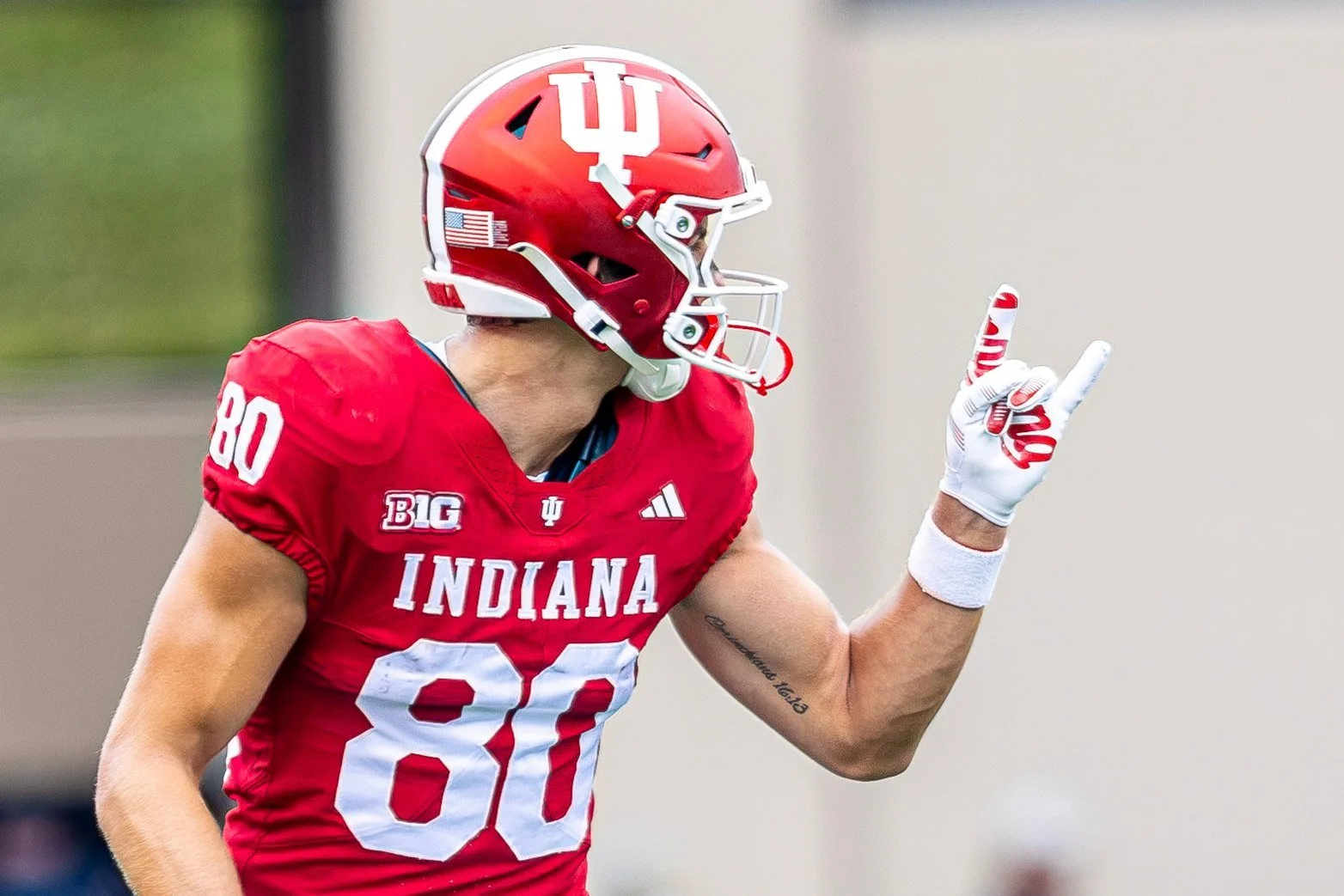 Indiana player in a crimson jersey pointing downfield to signal a first down.